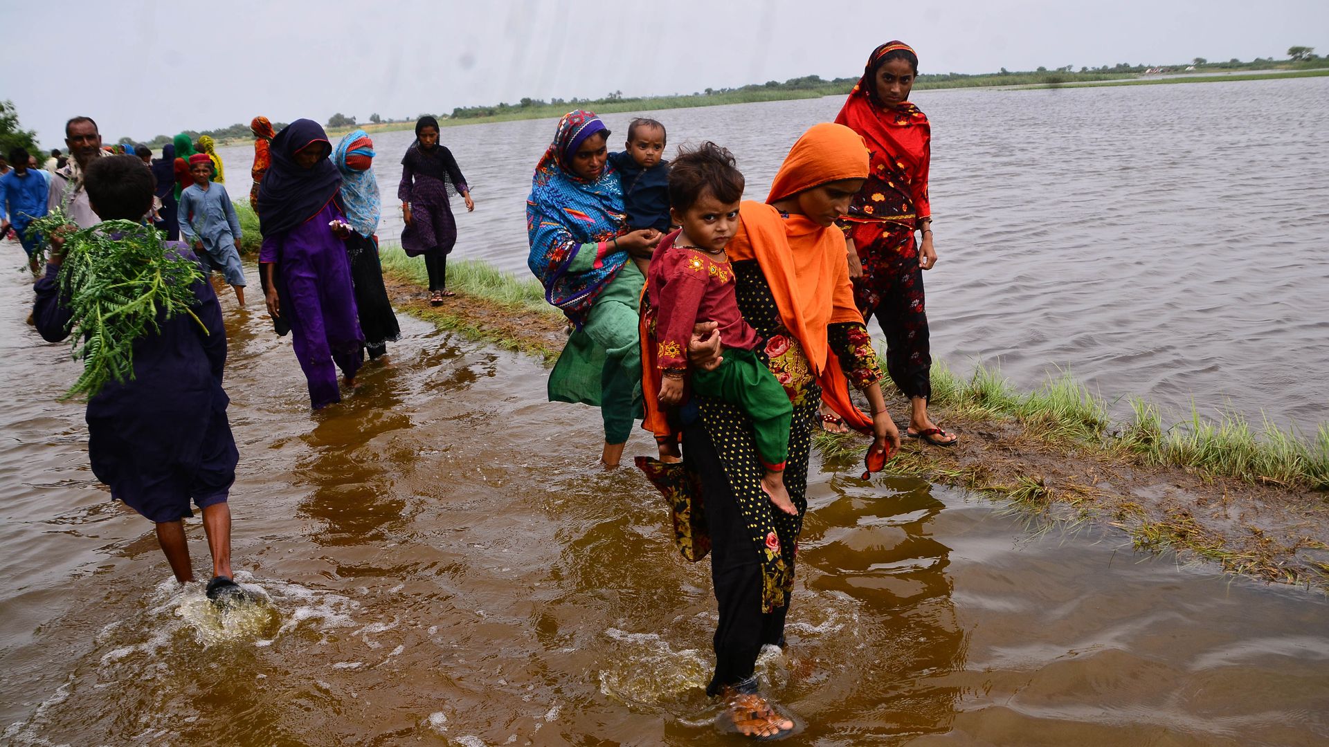 Pakistani people wade through floodwater following flash flood 