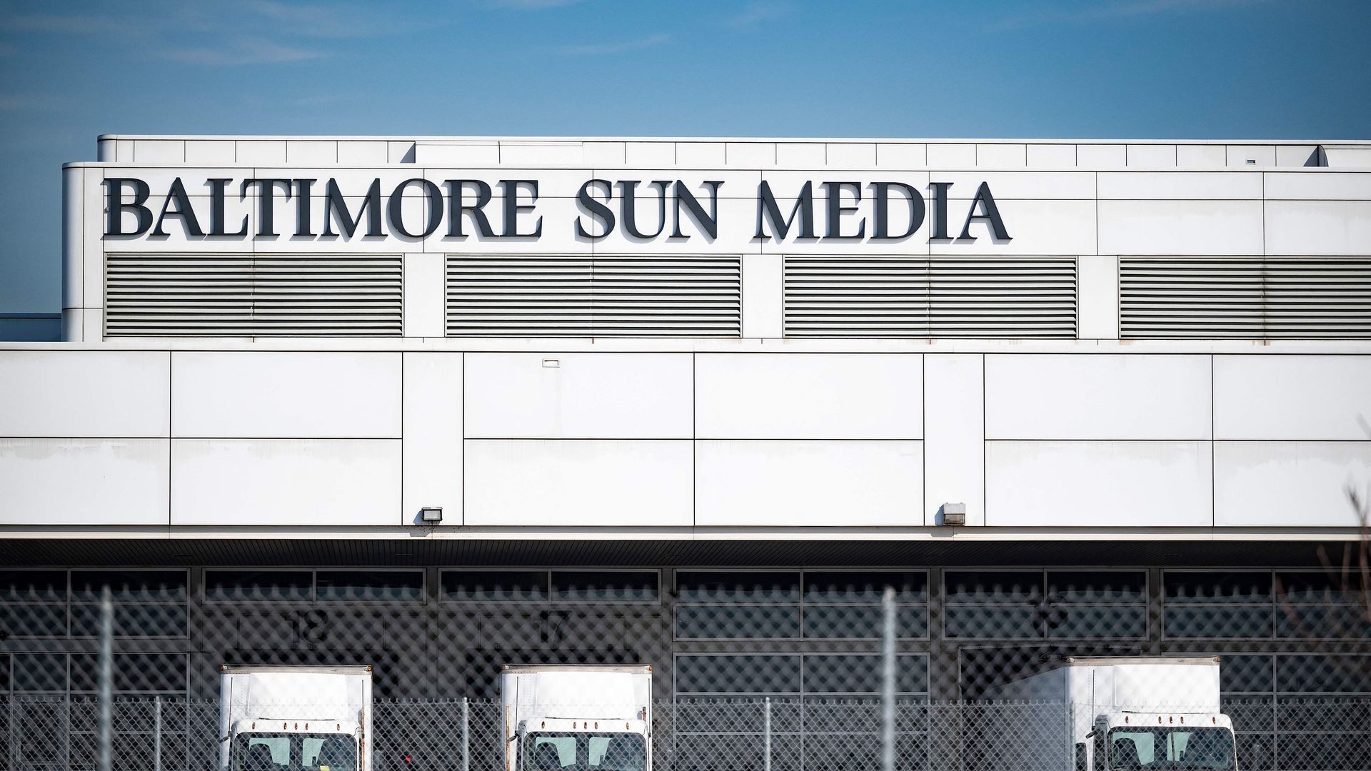 The exterior of the Baltimore Sun Media building, with delivery trucks parked outside.
