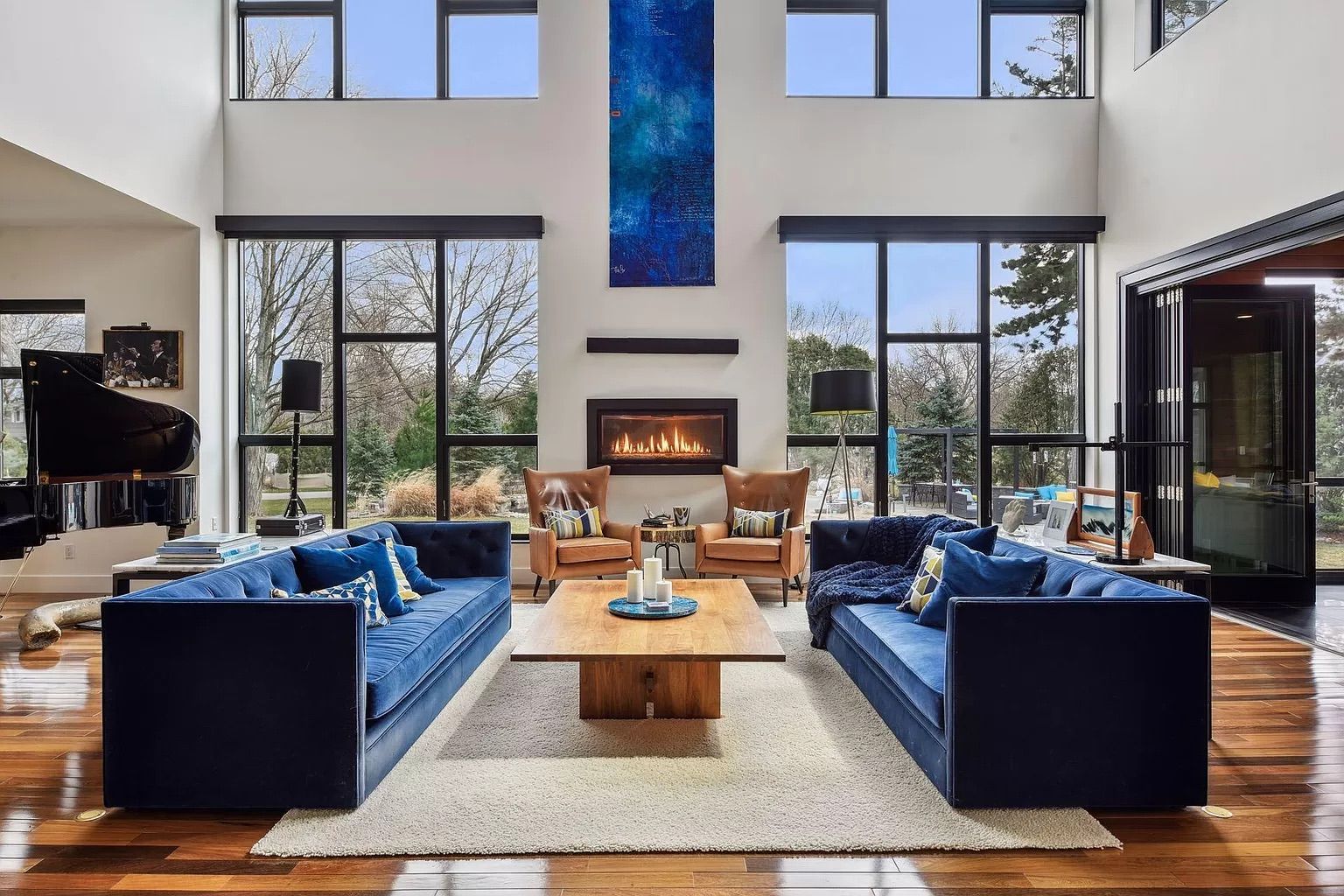 A living room with high ceilings, large windows and blue couches.