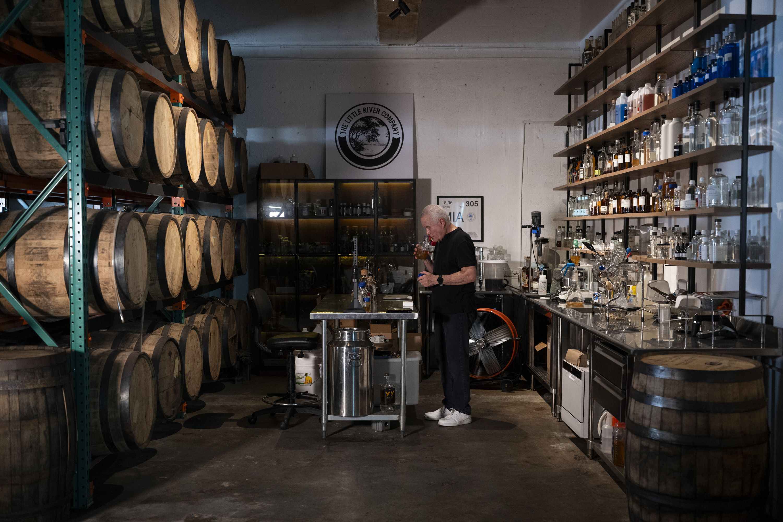 Distillery scene with wooden barrels on the left and bottle shelves on the right.