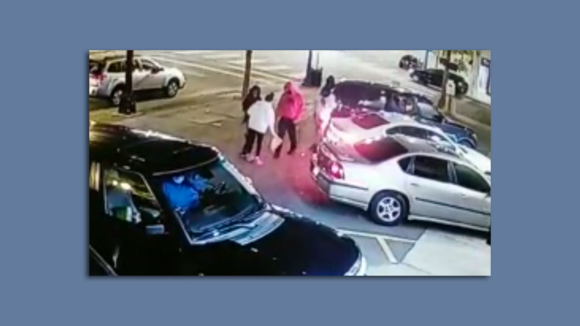 A woman in a white sweatshirt is surrounded by men in a parking lot 