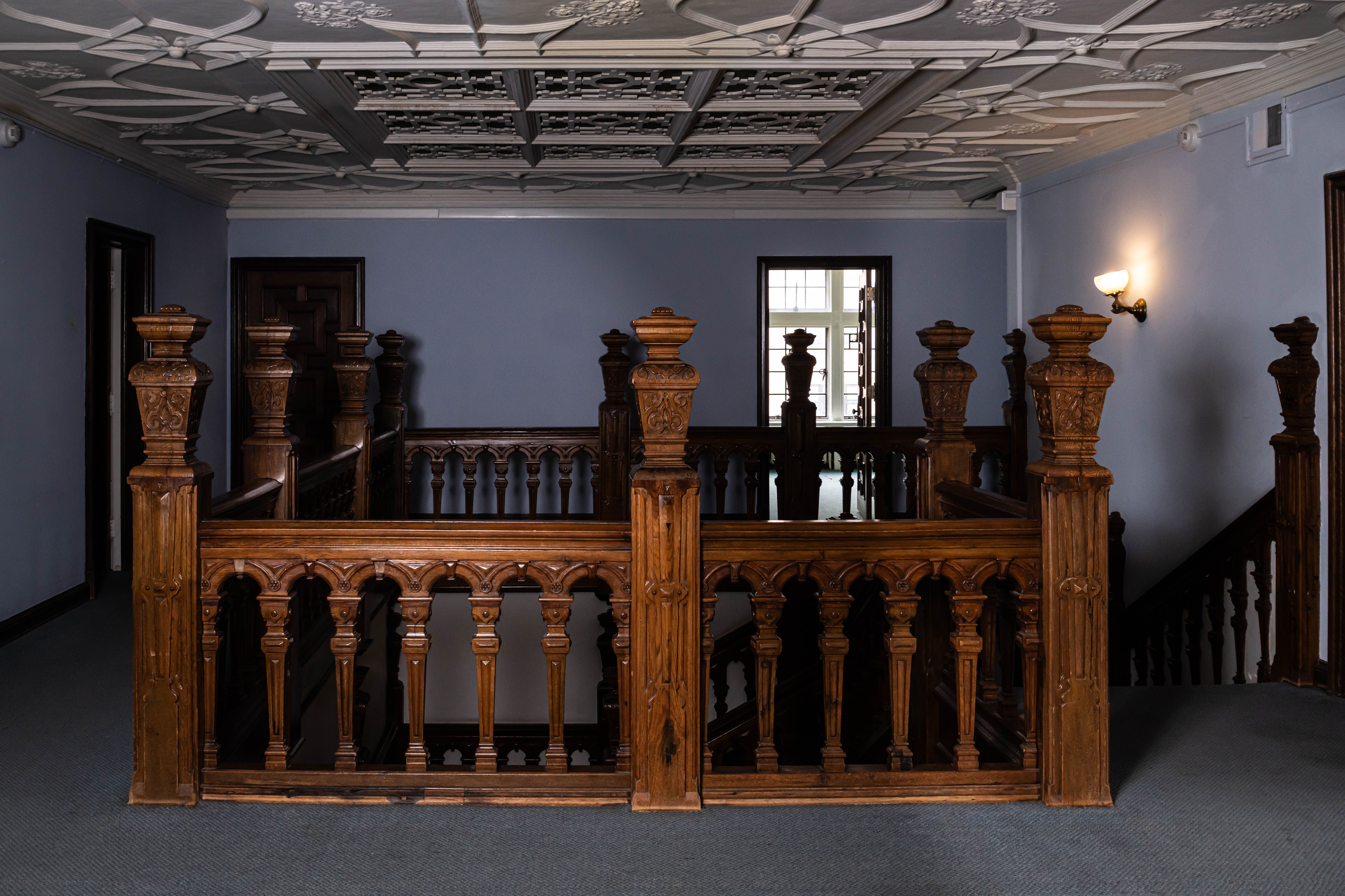 An elaborate wood staircase with purple walls around it.