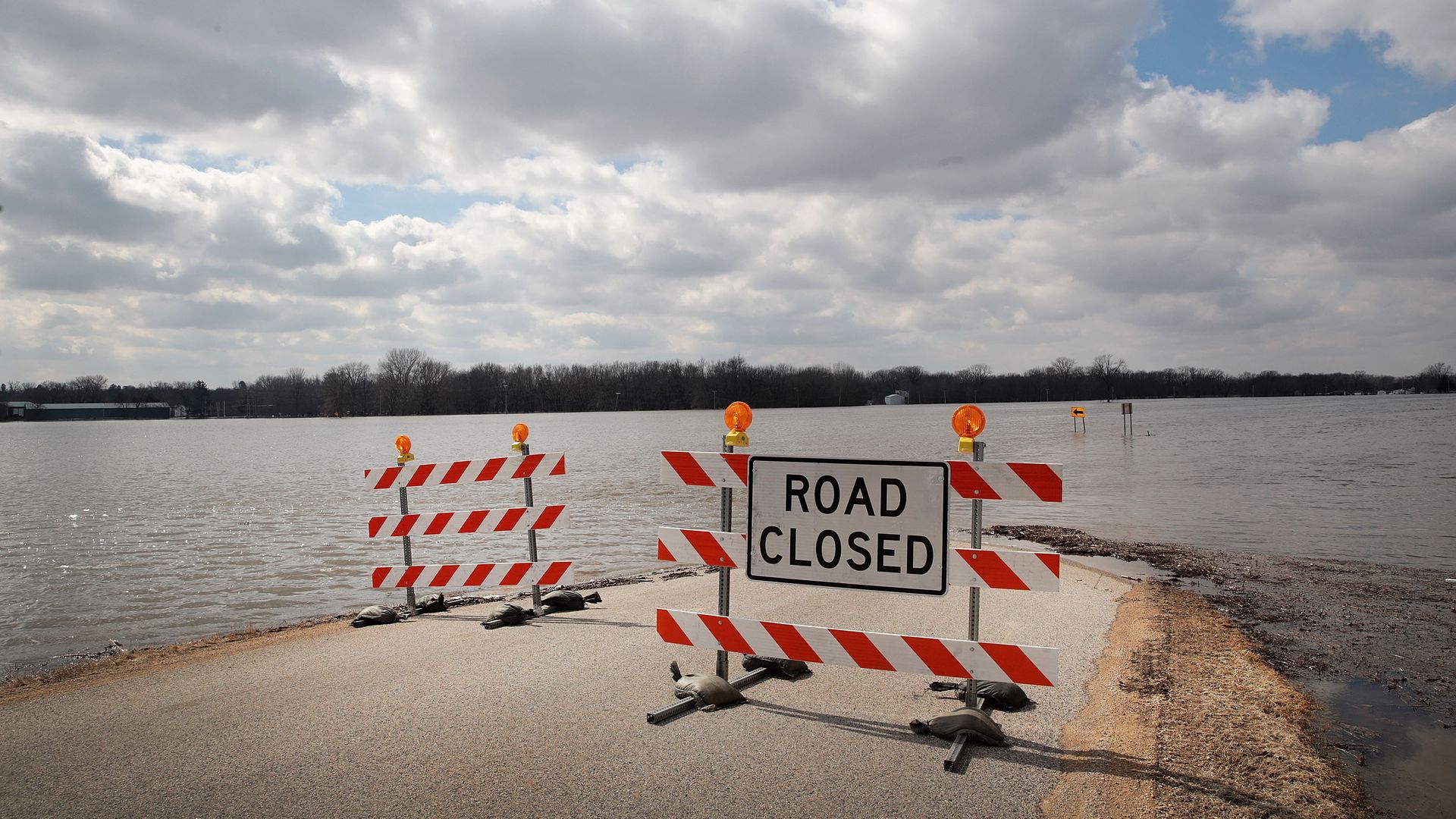 A road closed sign in front of a flooded road in the Midwest.