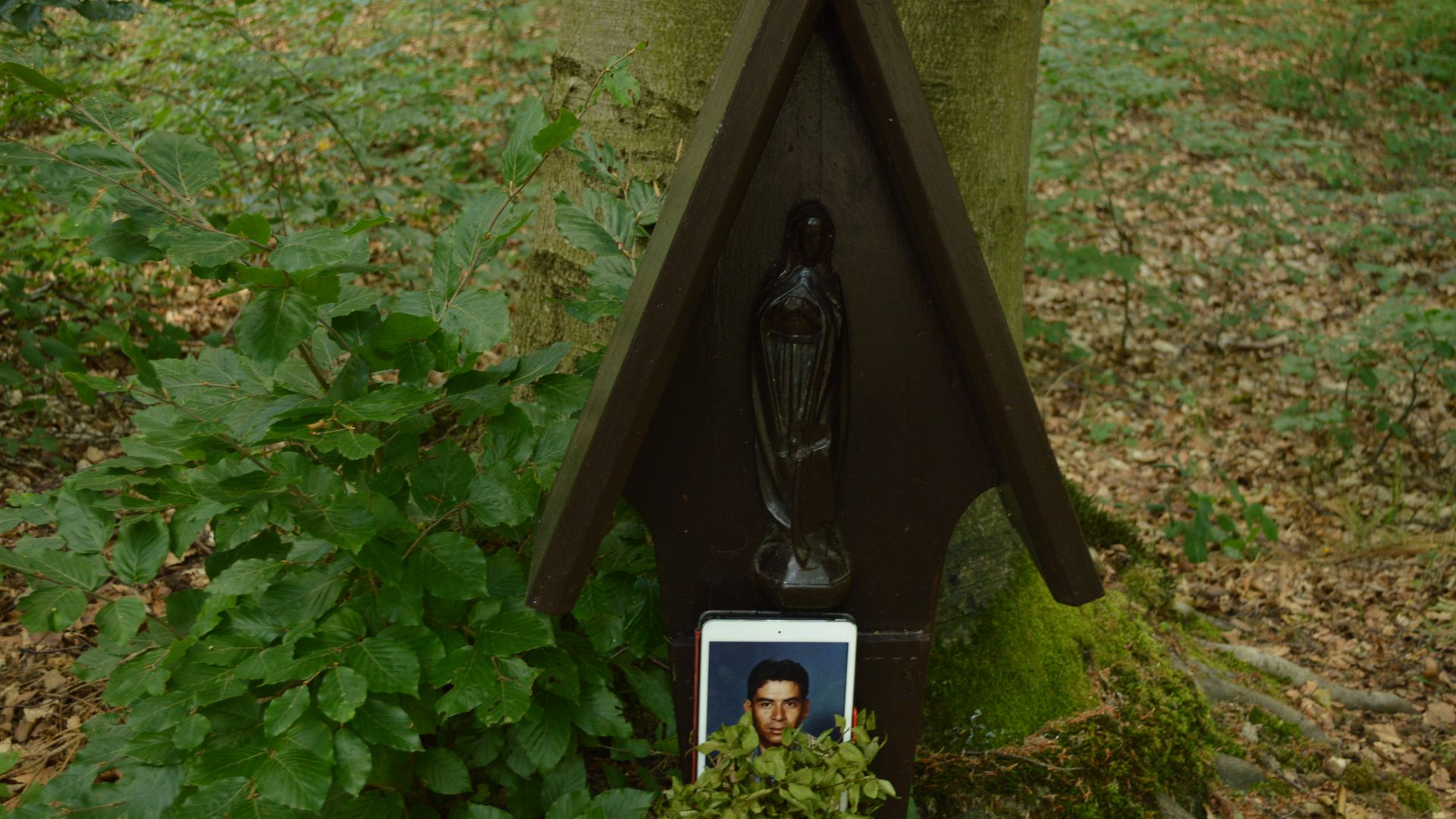 A photo of World War II Medal of Honor recipient Macario Garcia on an iPad Mini sits in front of a carving of the Virgin Mary Germany's Hürtgen Forest.