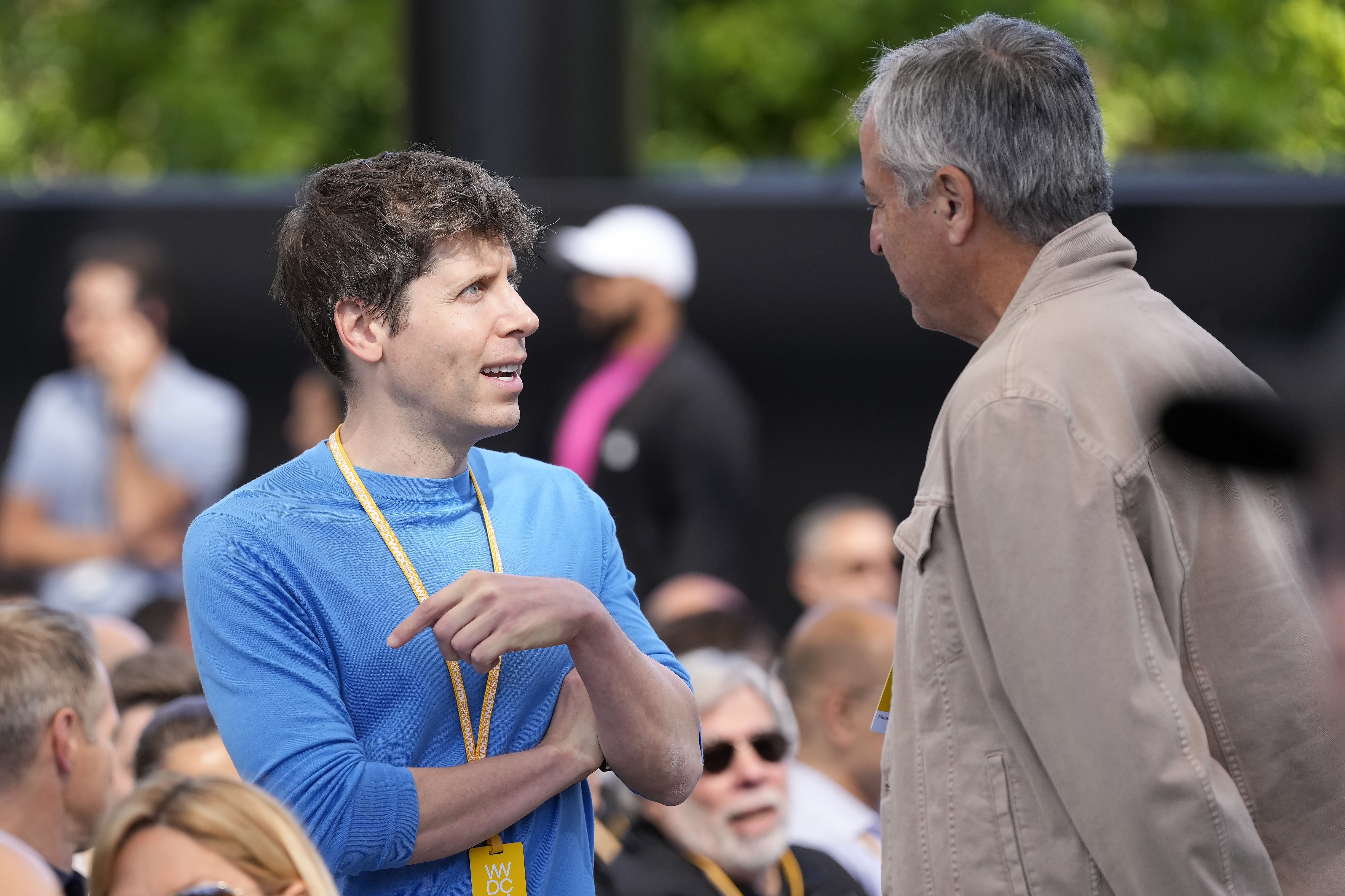 OpenAI CEO Sam Altman talks with Apple exec Eddy Cue at an Apple event in June.