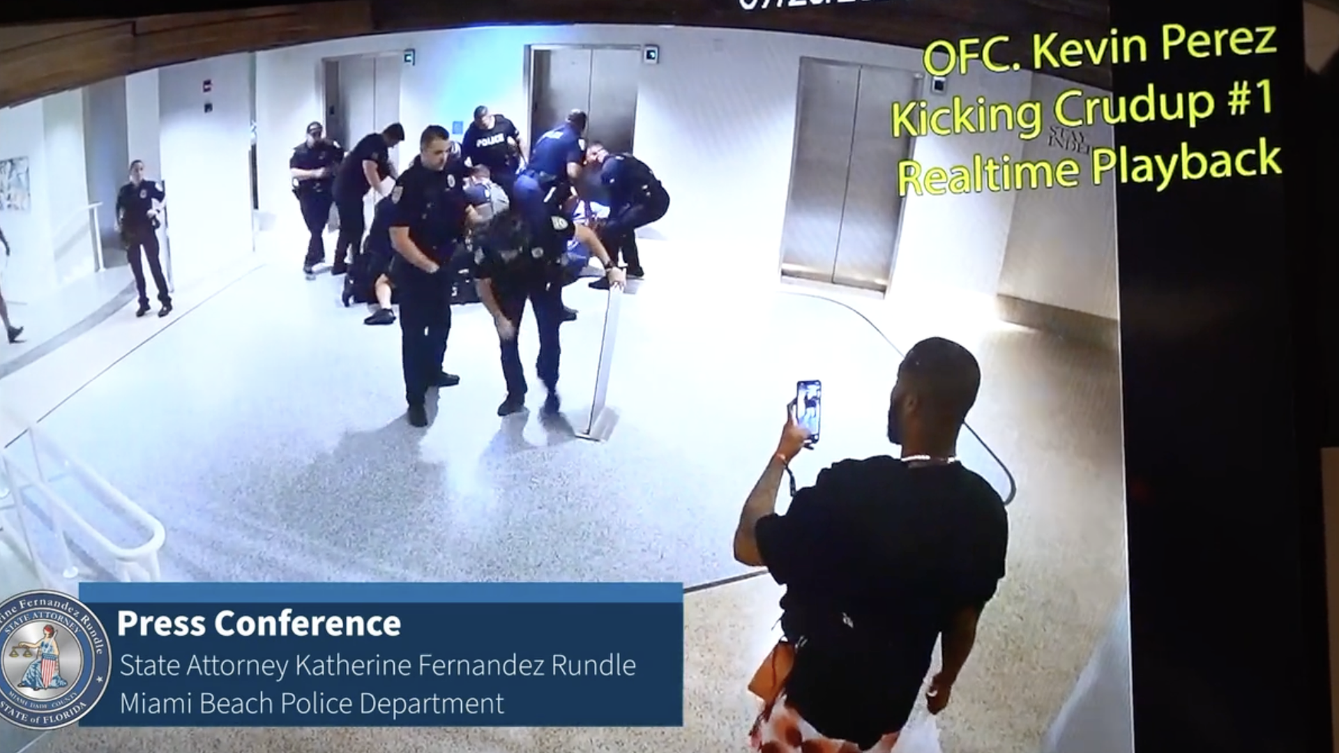 A screen shot from a surveillance video shows a man filming a group of police.