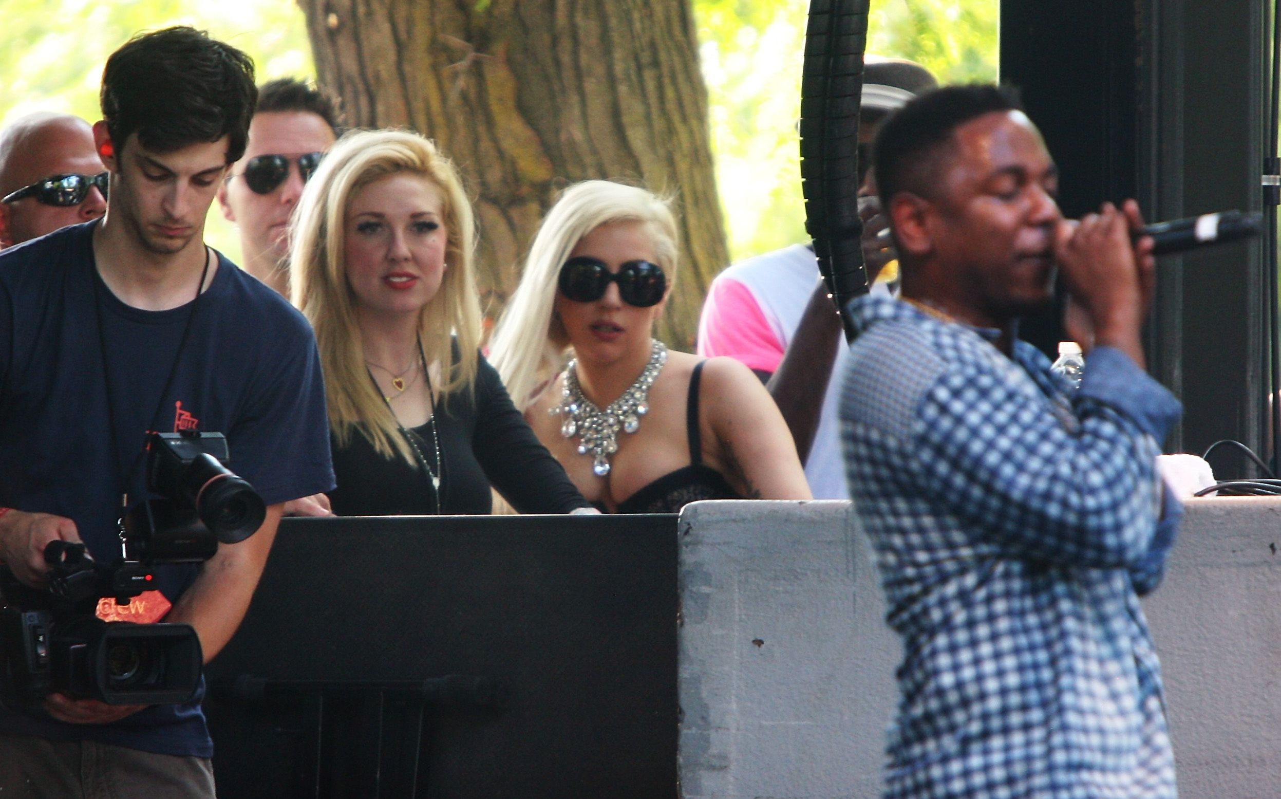 Lady Gaga in sunglasses looking on as Kendrick Lamar performs.