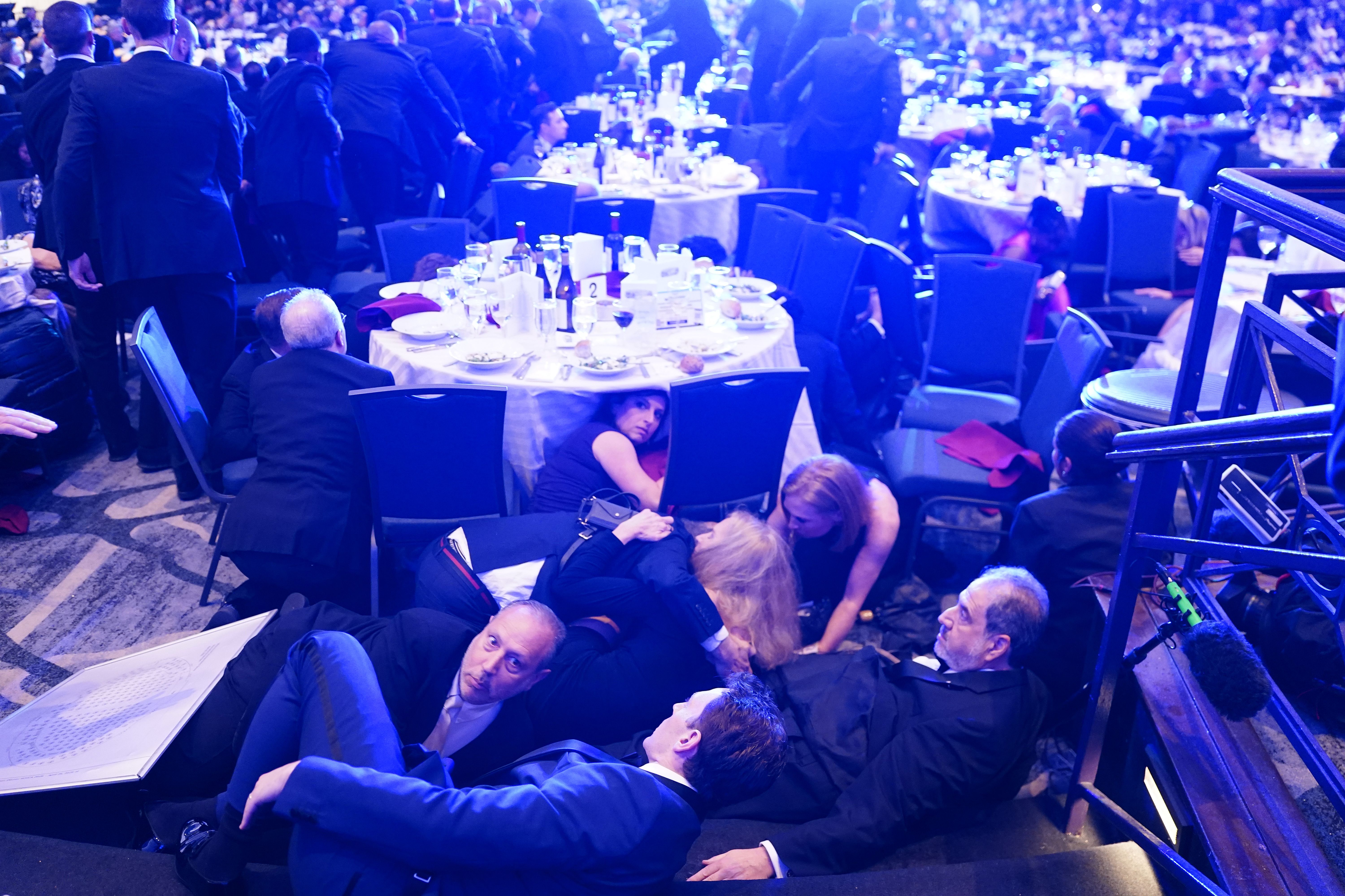 Attendees hide under tables after shots were heard at the White House Correspondents' Dinner