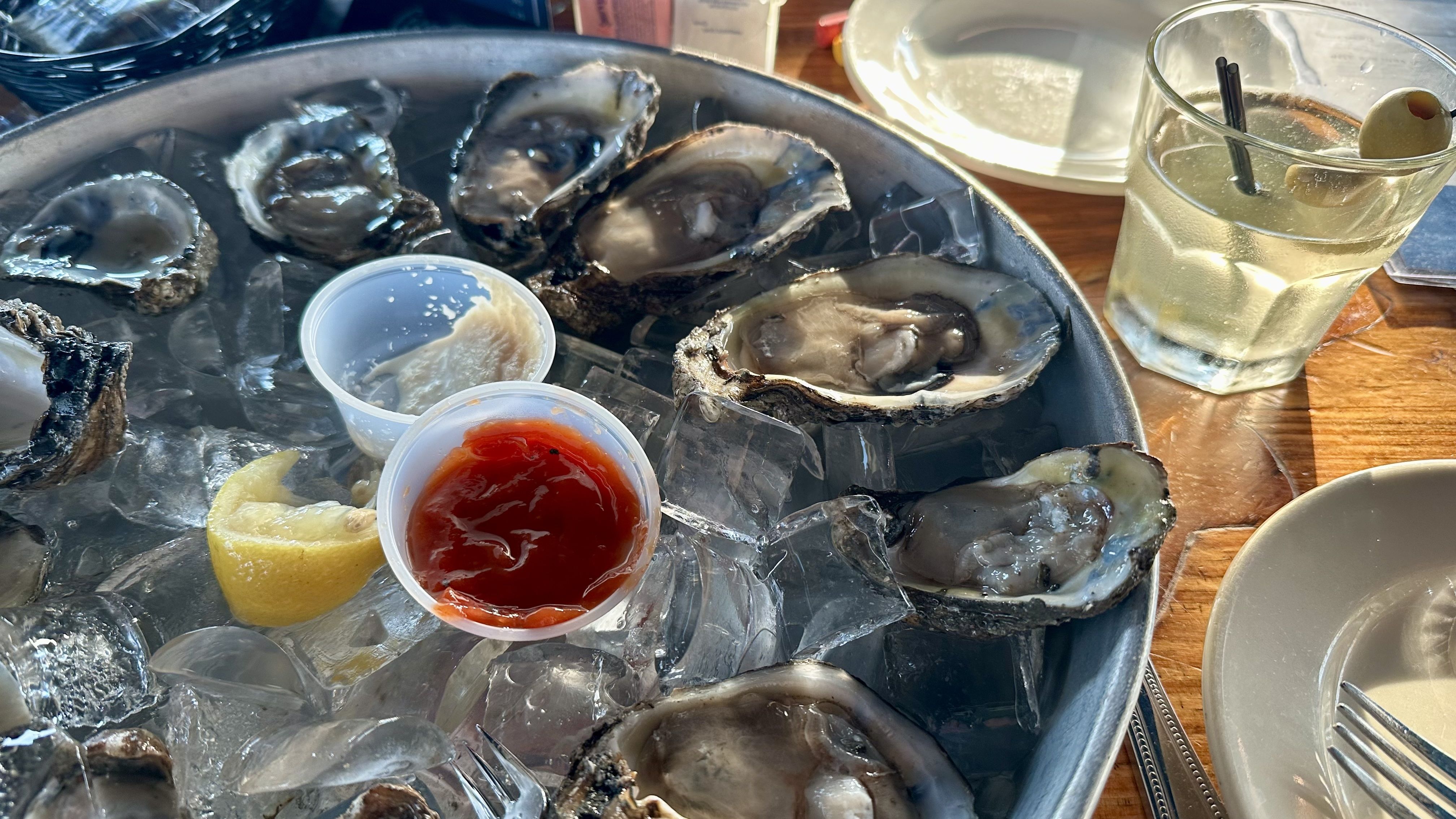 Photo shows a dozen oysters with a drink.
