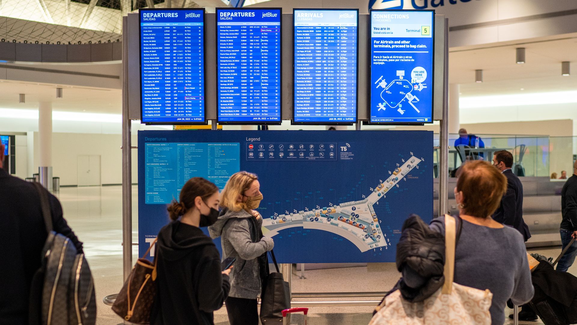 Airline passengers check the departure and arrival board January 28, 2022 at John F. Kennedy International Airport