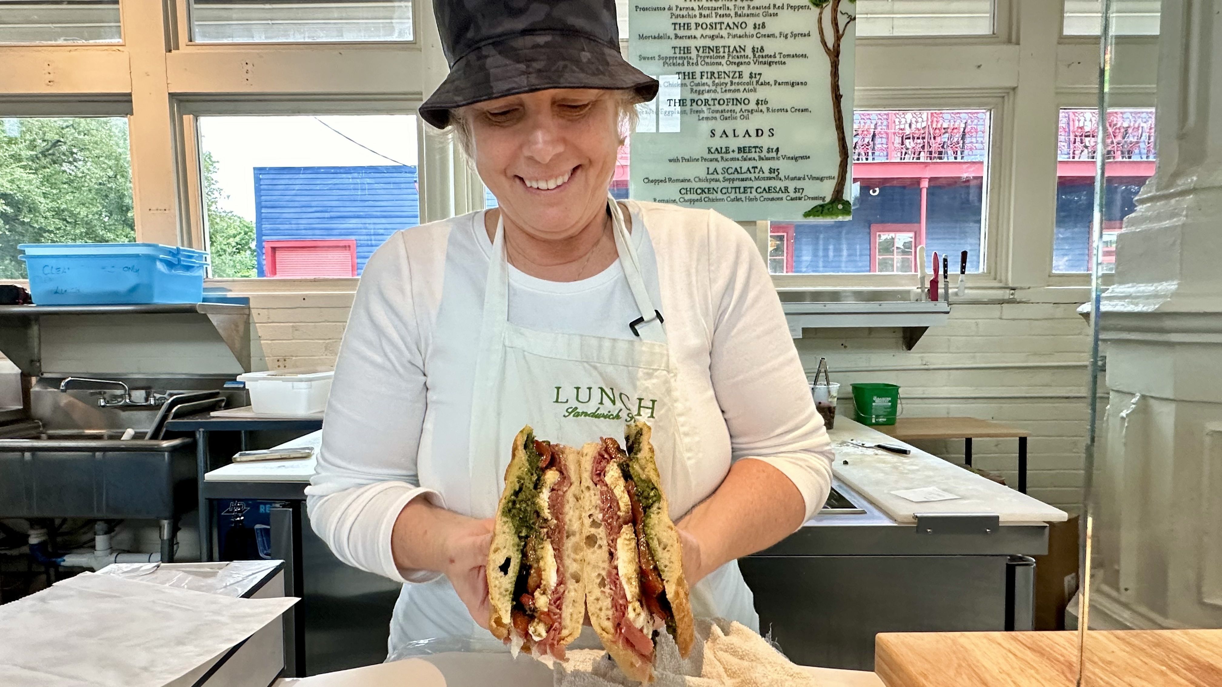 Photo shows a woman holding a sandwich.