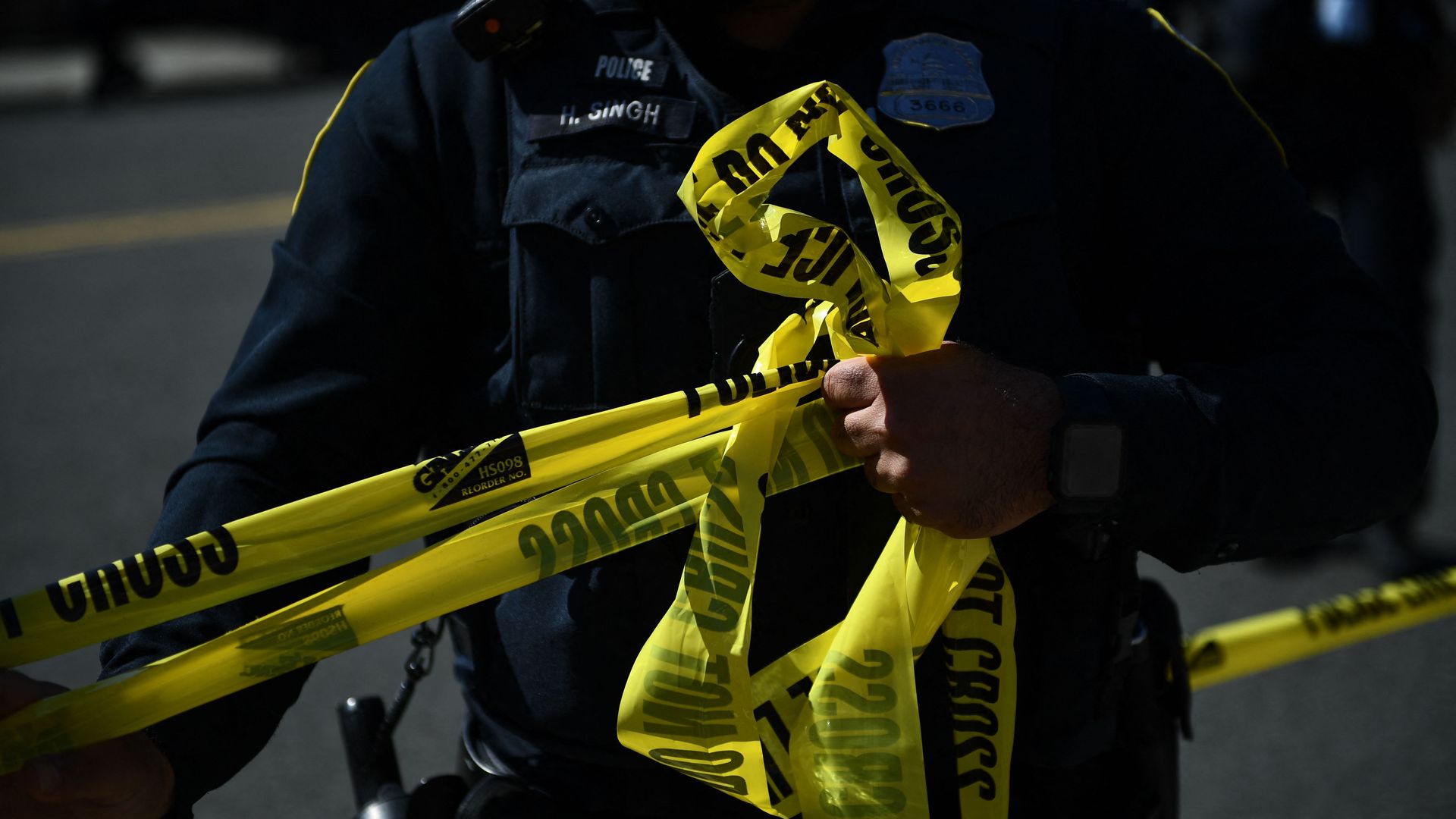 An officer holds police caution tape