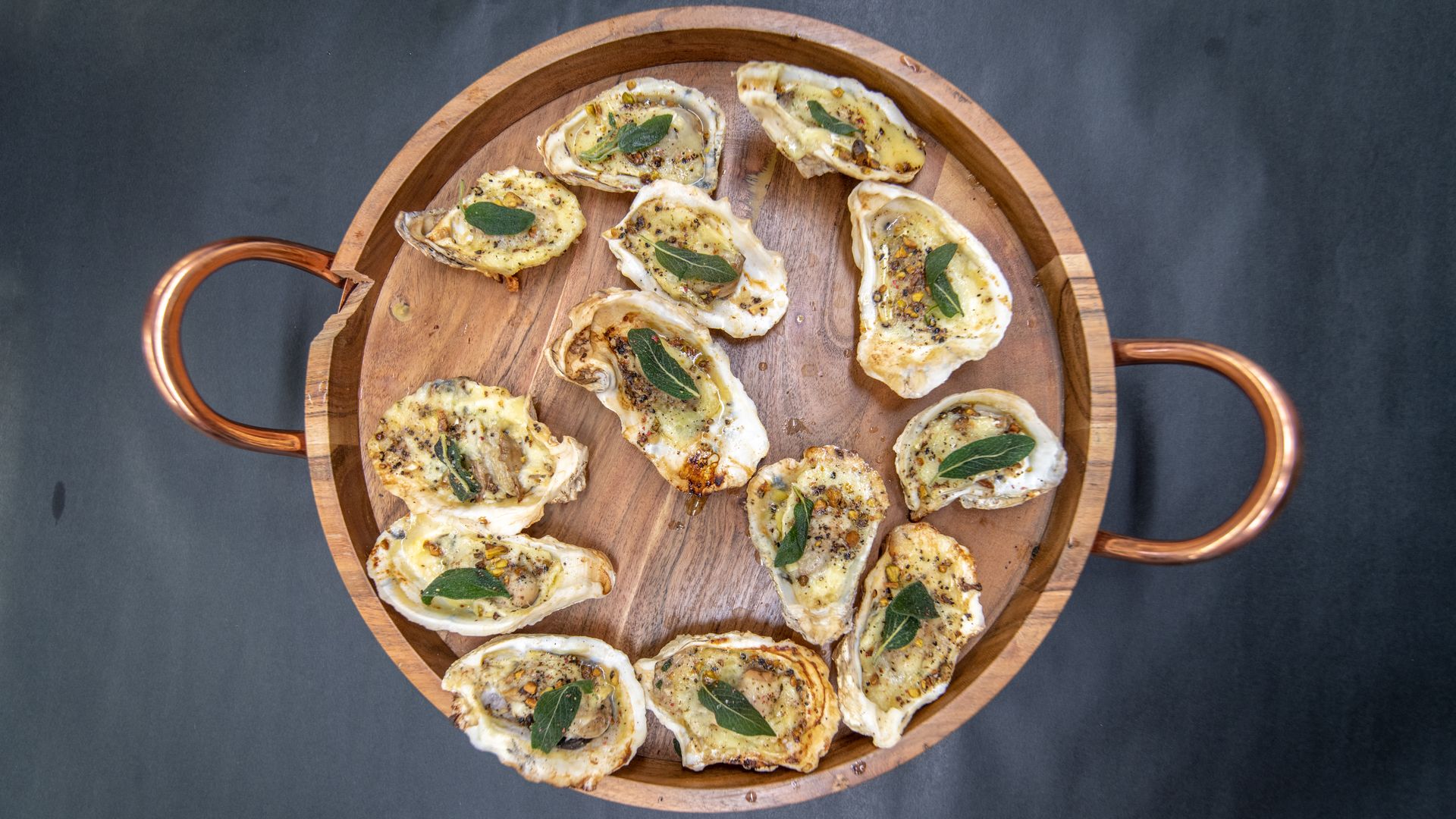 A table with grilled oysters topped with a sage leaf