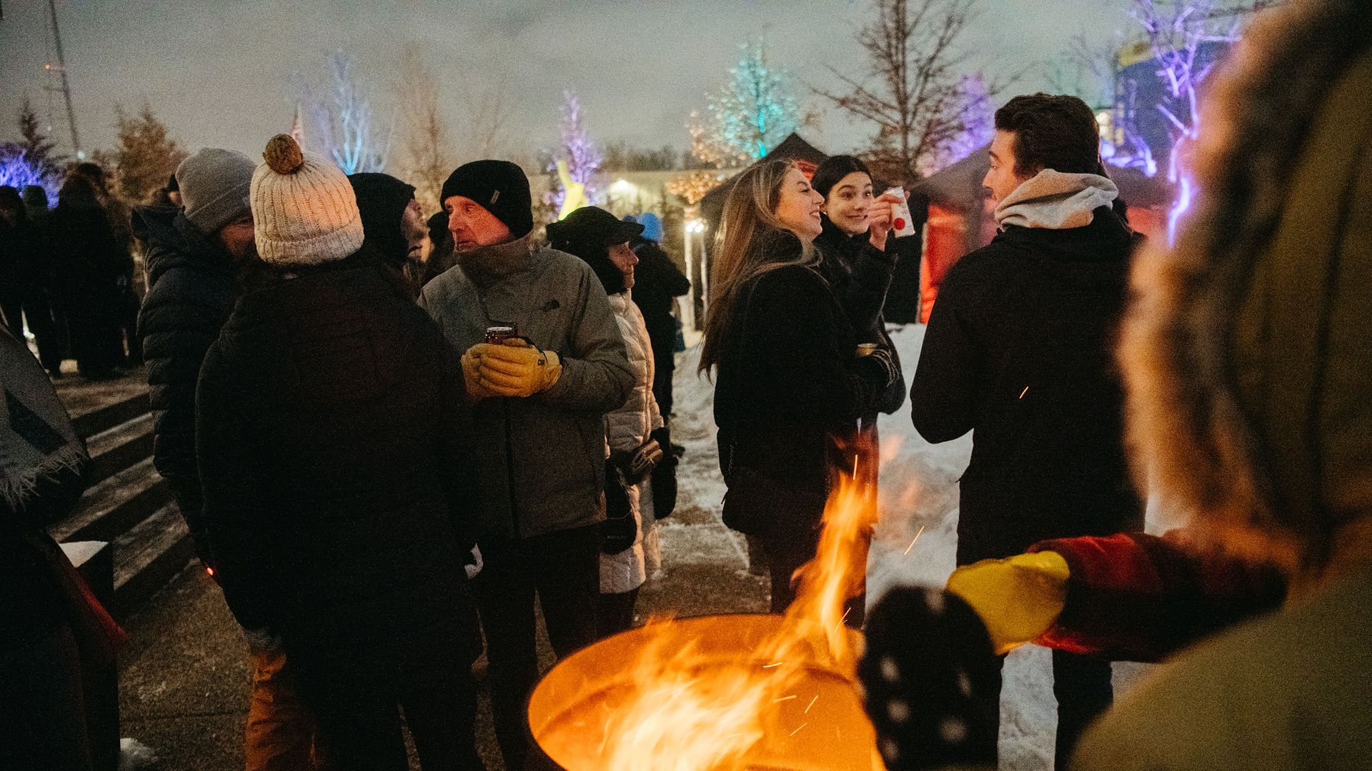 people bunded up around a fire outside socializing