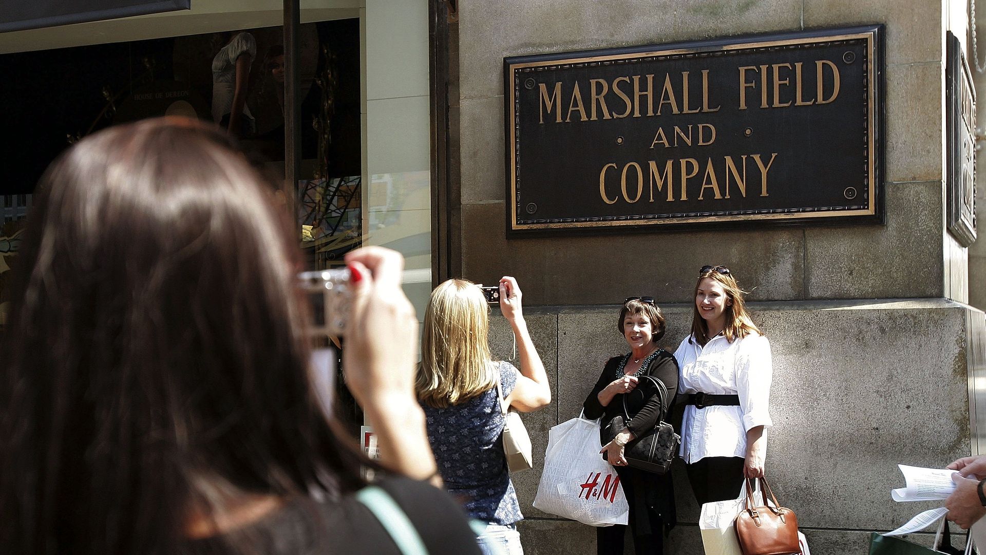 Photo of people taking photos in front of a sign that says "Marshall Field and Company." 