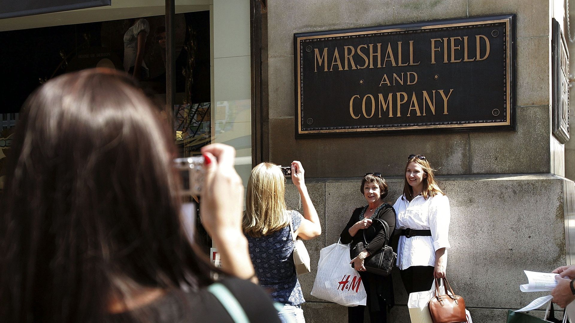 Photo of people taking photos in front of a sign that says "Marshall Field and Company."