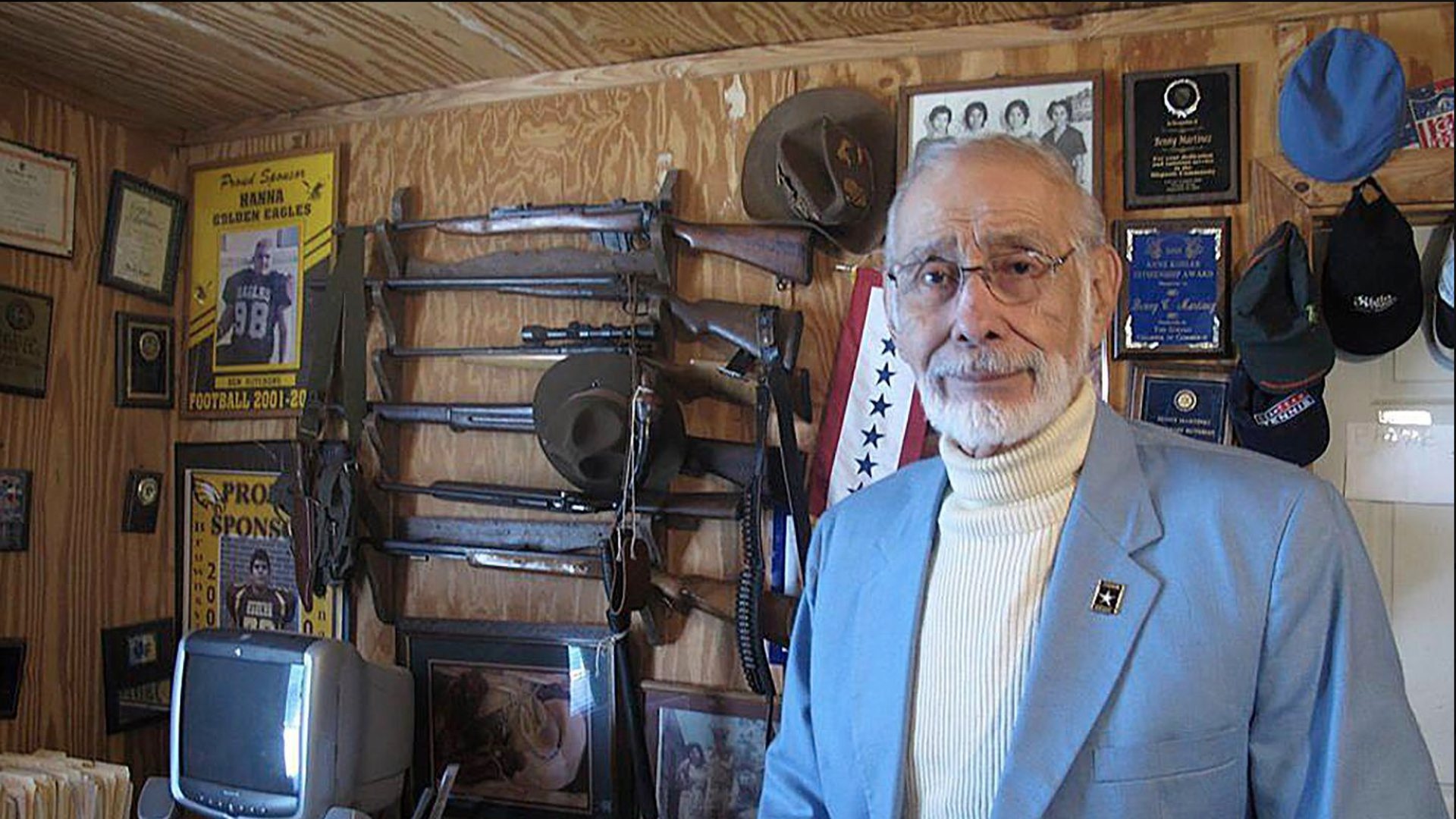 In this March 11, 2013 photo, Benny Martinez, a Mexican American civil rights leader who helped organize the historic Latino gala with President John F. Kennedy, stands in front of a gun collection at his Goliad, Texas, home. 