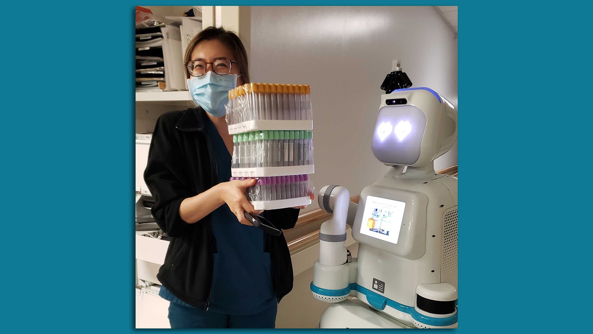 A person stands with a robot at a medical facility.
