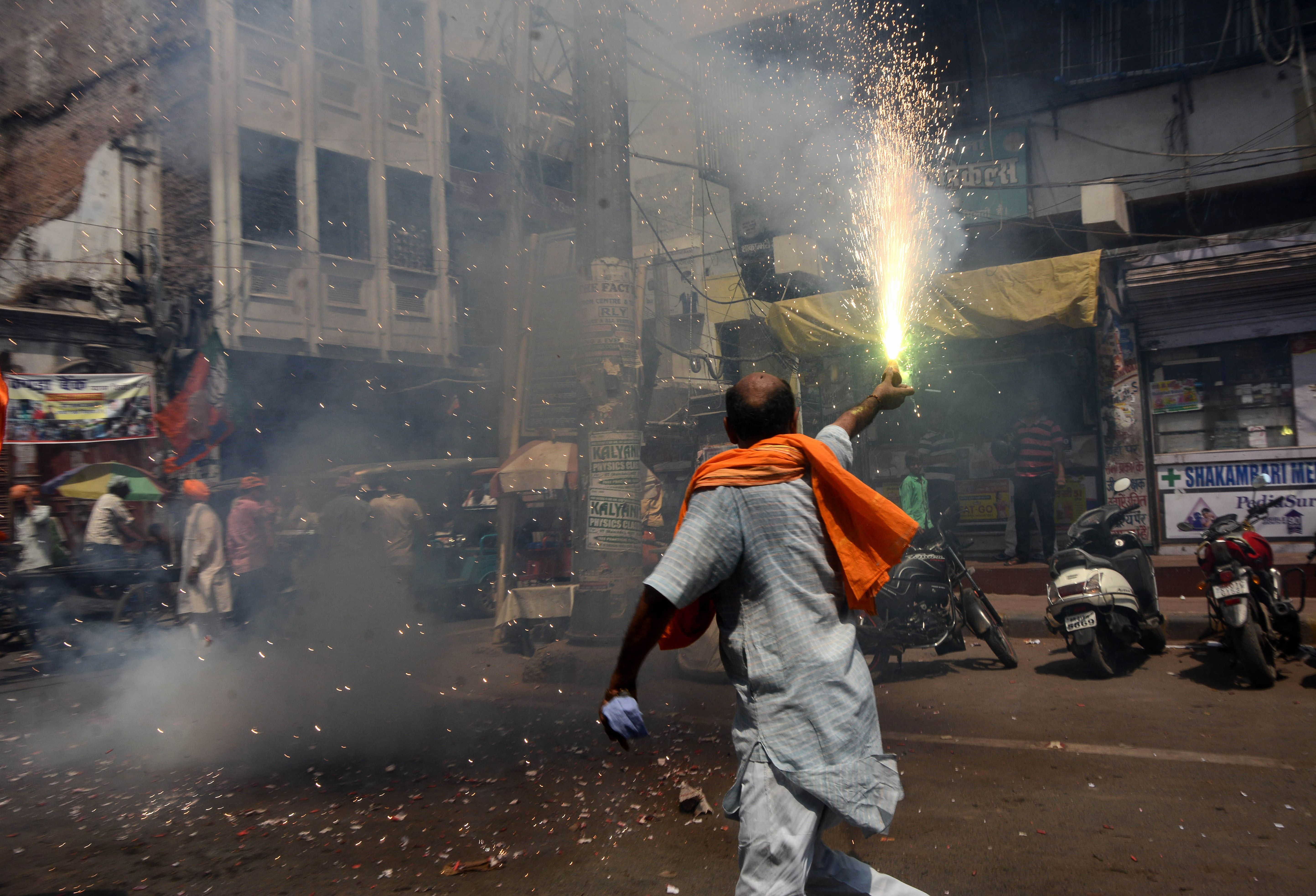 An Indian supporter of the Bharatiya Janata Party (BJP) lets off a firecracker.