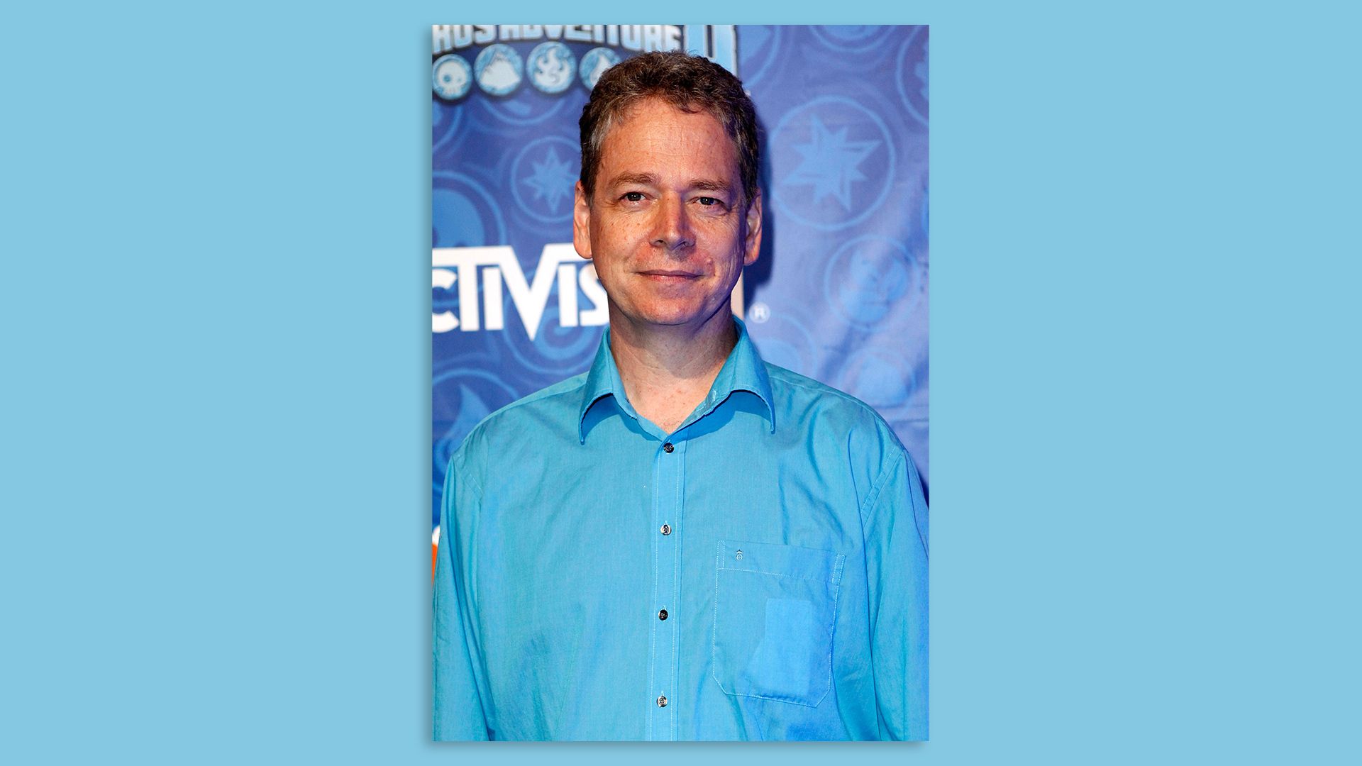 Photo of a man in a blue dress shirt in front of an Activision logo
