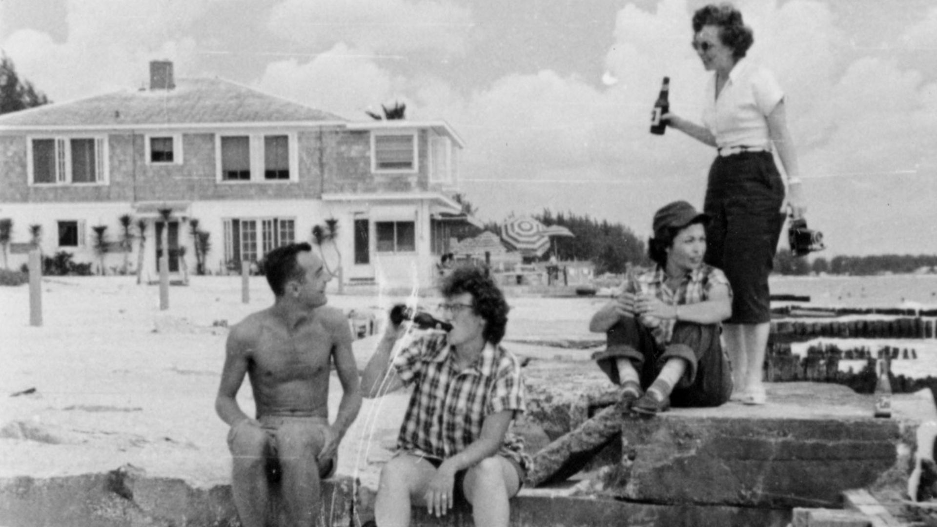 a black and white photo of people drinking beers on the beach