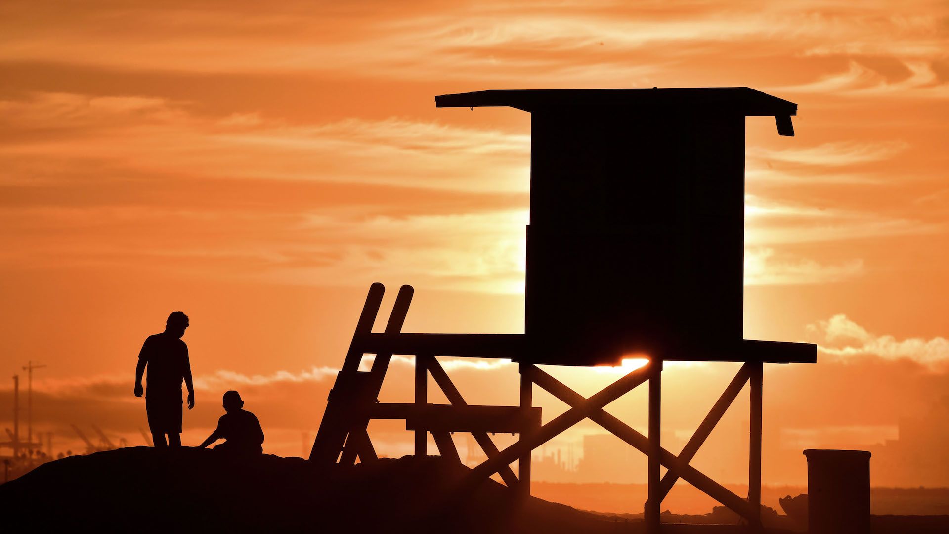 Children play beside a lifeguard tower as sunset approaches at Sunset Beach in Huntington Beach, California on July 21, 2018. 