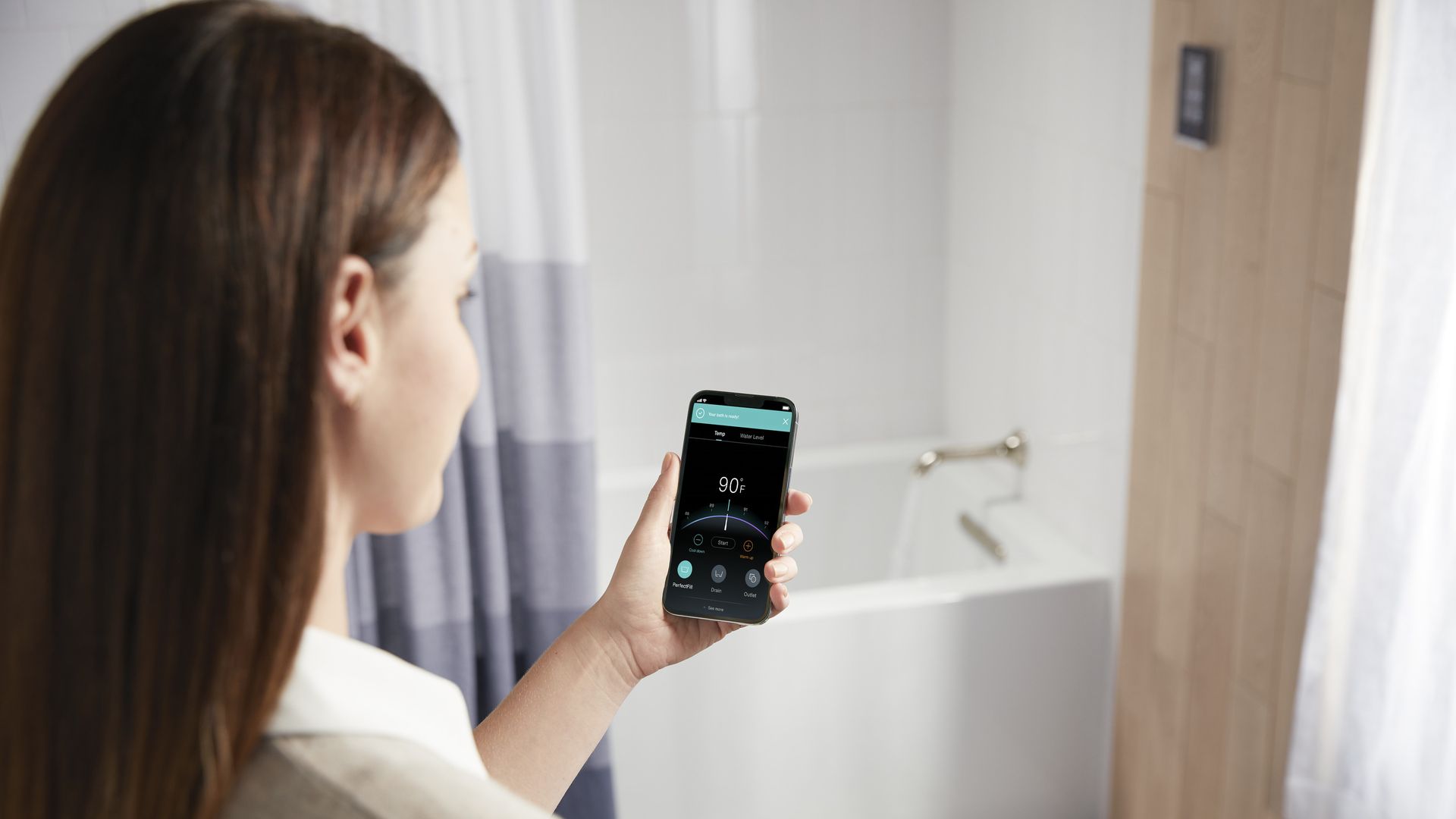 Image of a woman using a smartphone app to fill her bathtub