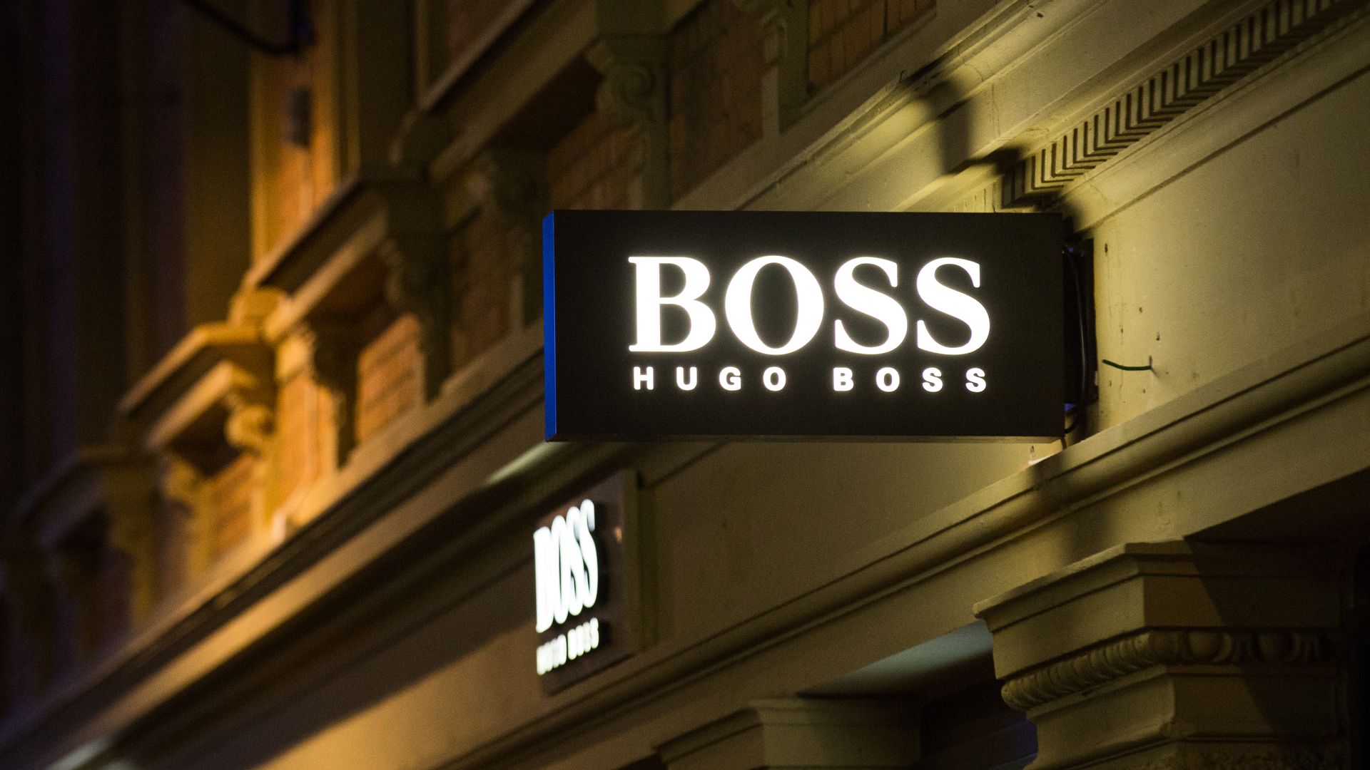 A lighted Hugo Boss sign hangs above a storefront.