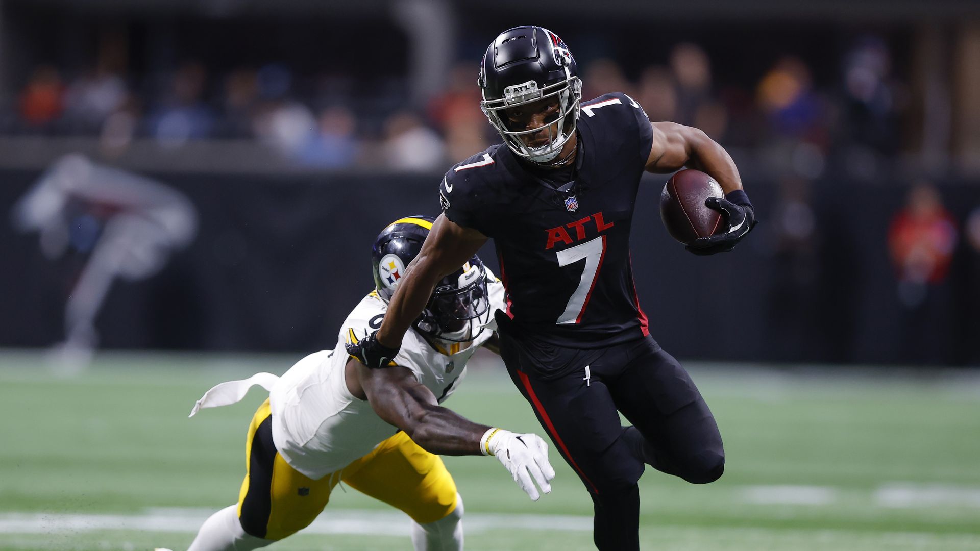 A man in a black uniform with number 7 runs with a football 
