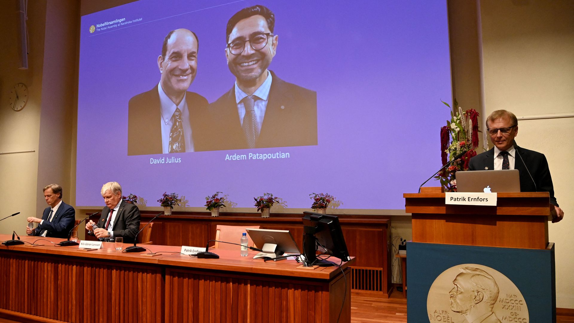 Members of the Nobel Committee sit in front of a screen displaying the winners of the prize in Physiology or Medicine at the Karolinska Institute in Stockholm.