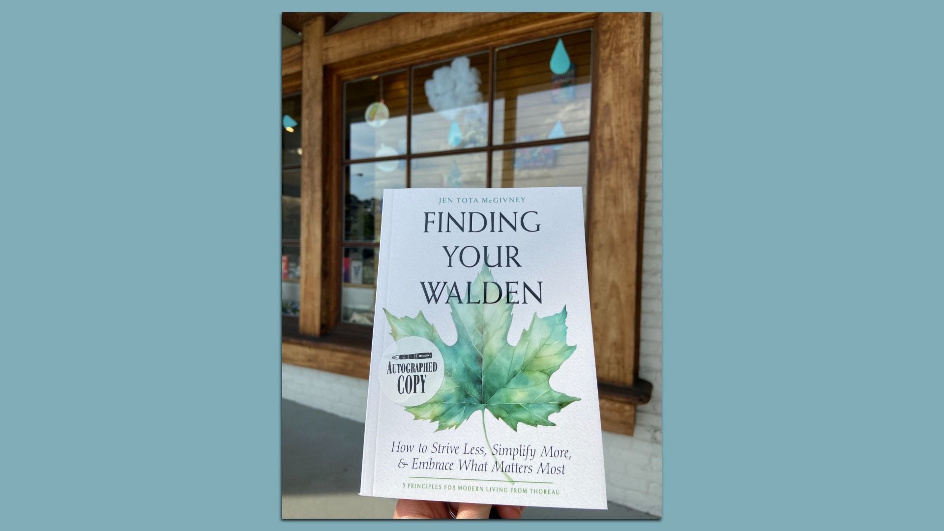 A book is held in front of a bookshop. 