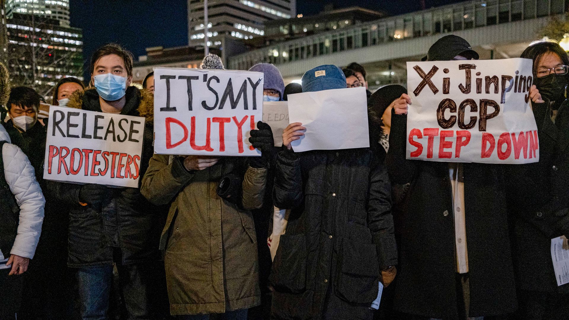 Protesters holding white papers and placards during a solidarity rally in Boston