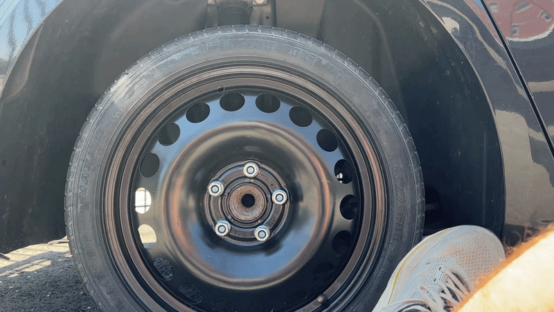 Gif of a foot wearing a tennis shoe kicking the side of a car wheel as part of a demonstration for how to jar it loose.