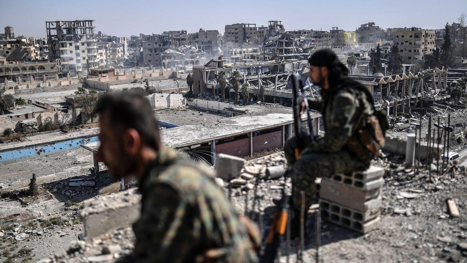 Fighters of the Syrian Democratic Forces (SDF) stand guard on a rooftop.
