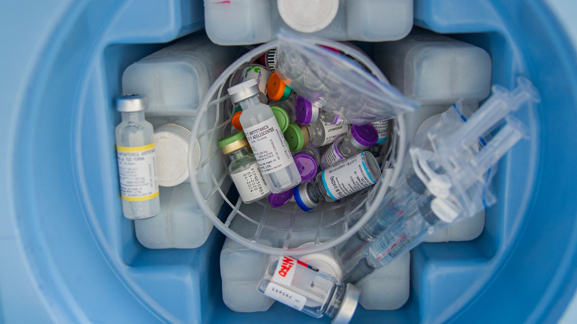 Photo of a bucket of medical supplies that include vaccines and syringes