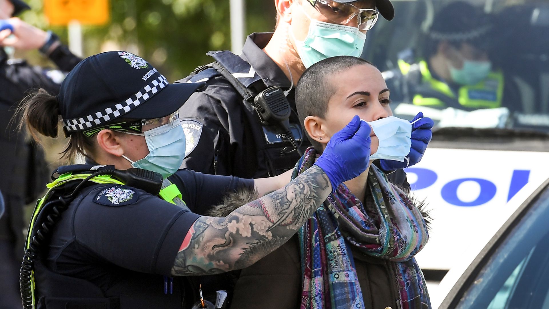 Police place a face mask on an arrested protester at the Shrine of Remembrance in Melbourne on September 5, 2020 during an anti-lockdown rally