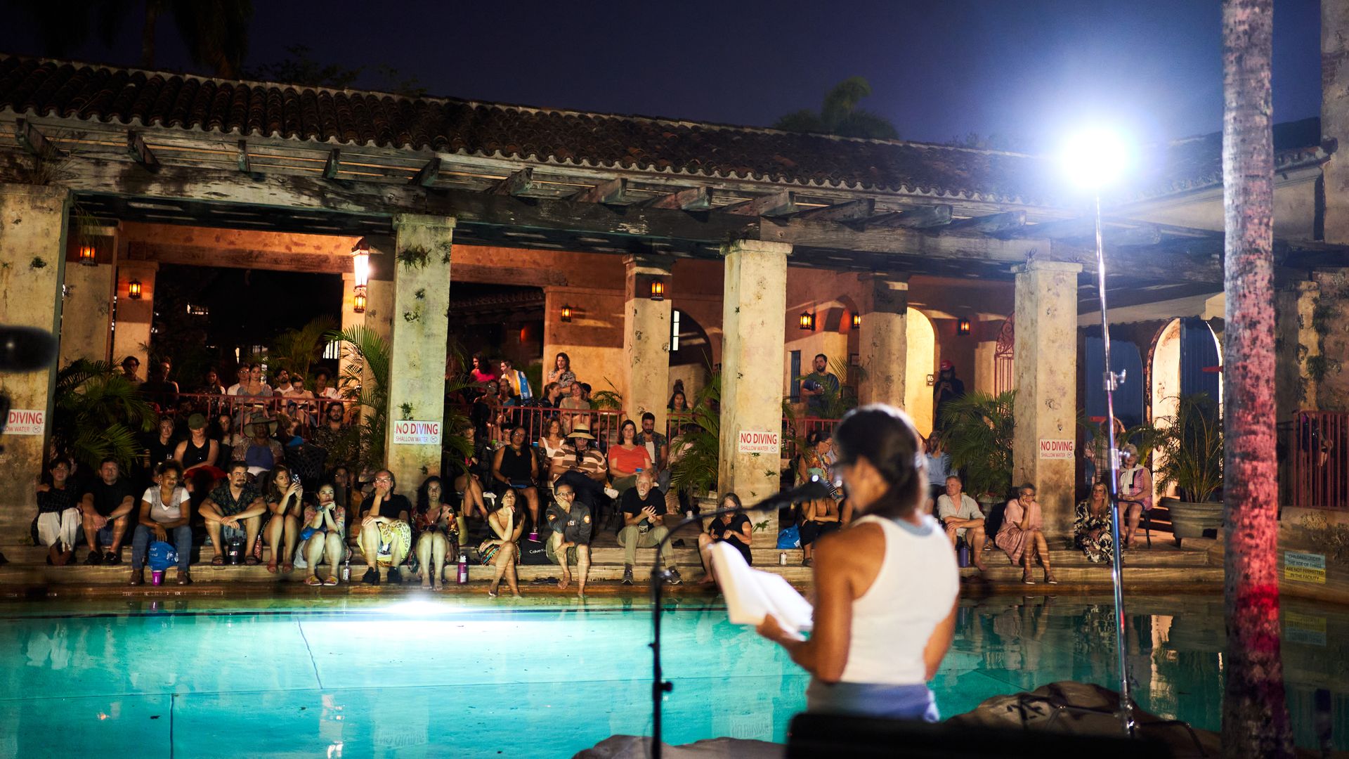 A person reading a poem in front of a large audience.