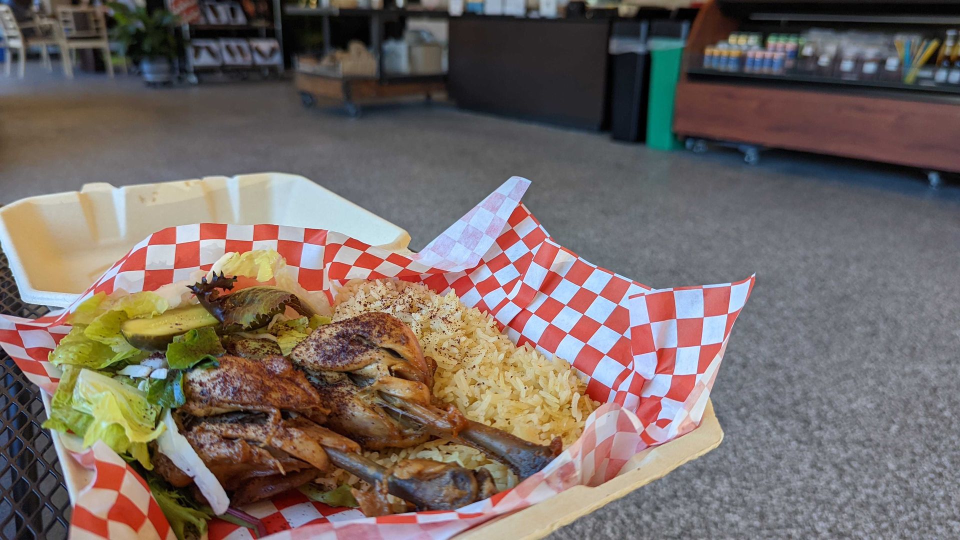 A plate of chicken in a to-go box.