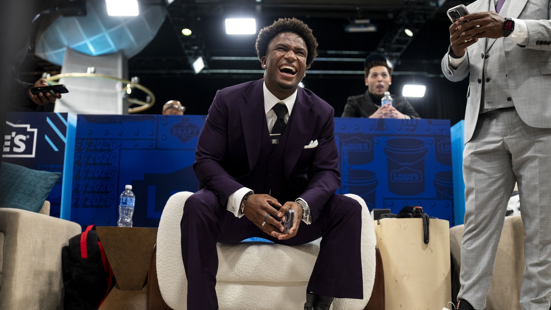 Caleb Downs sits on a chair wearing a suit, smiling