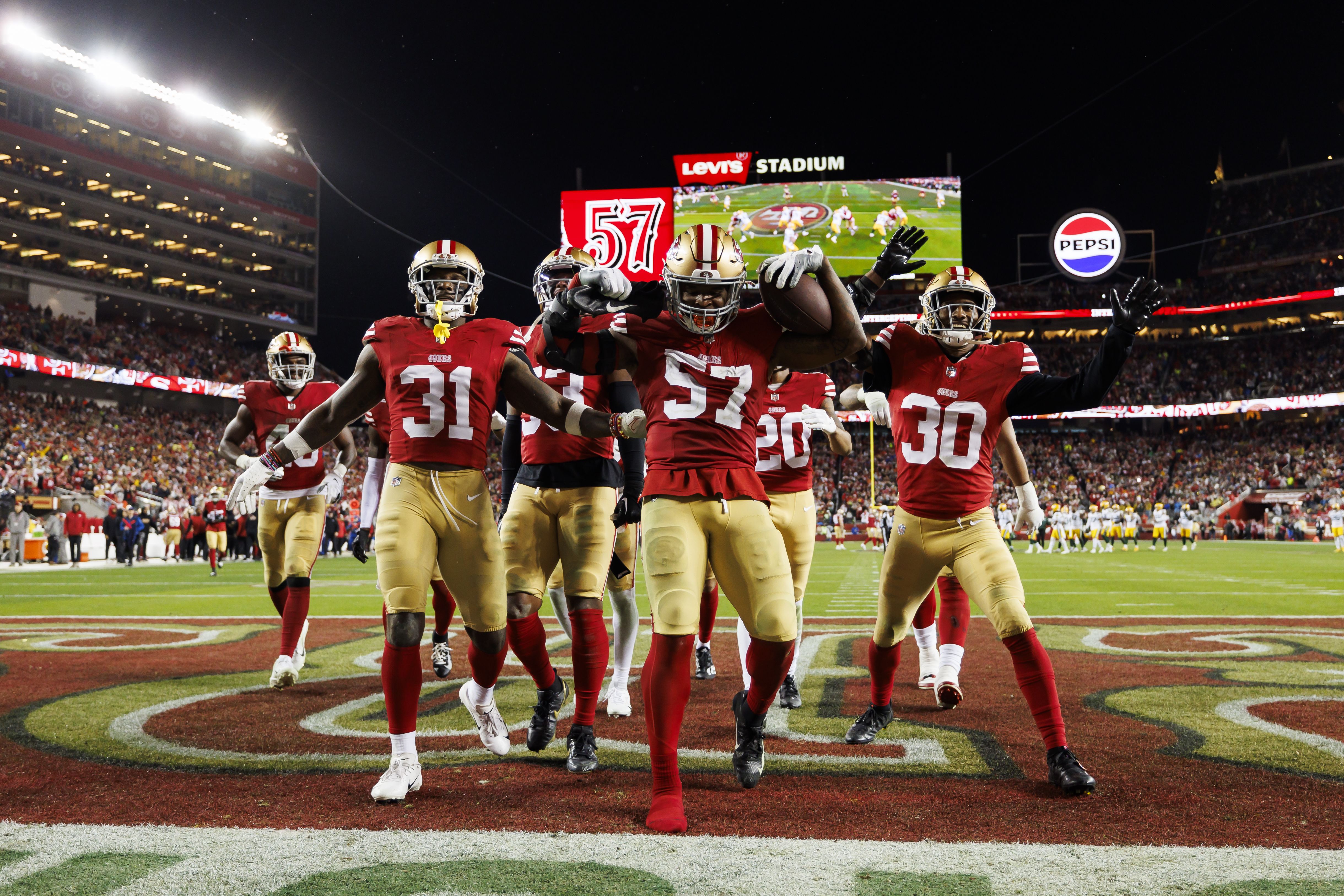 Photo of football players celebrating in front of a camera during a game. 