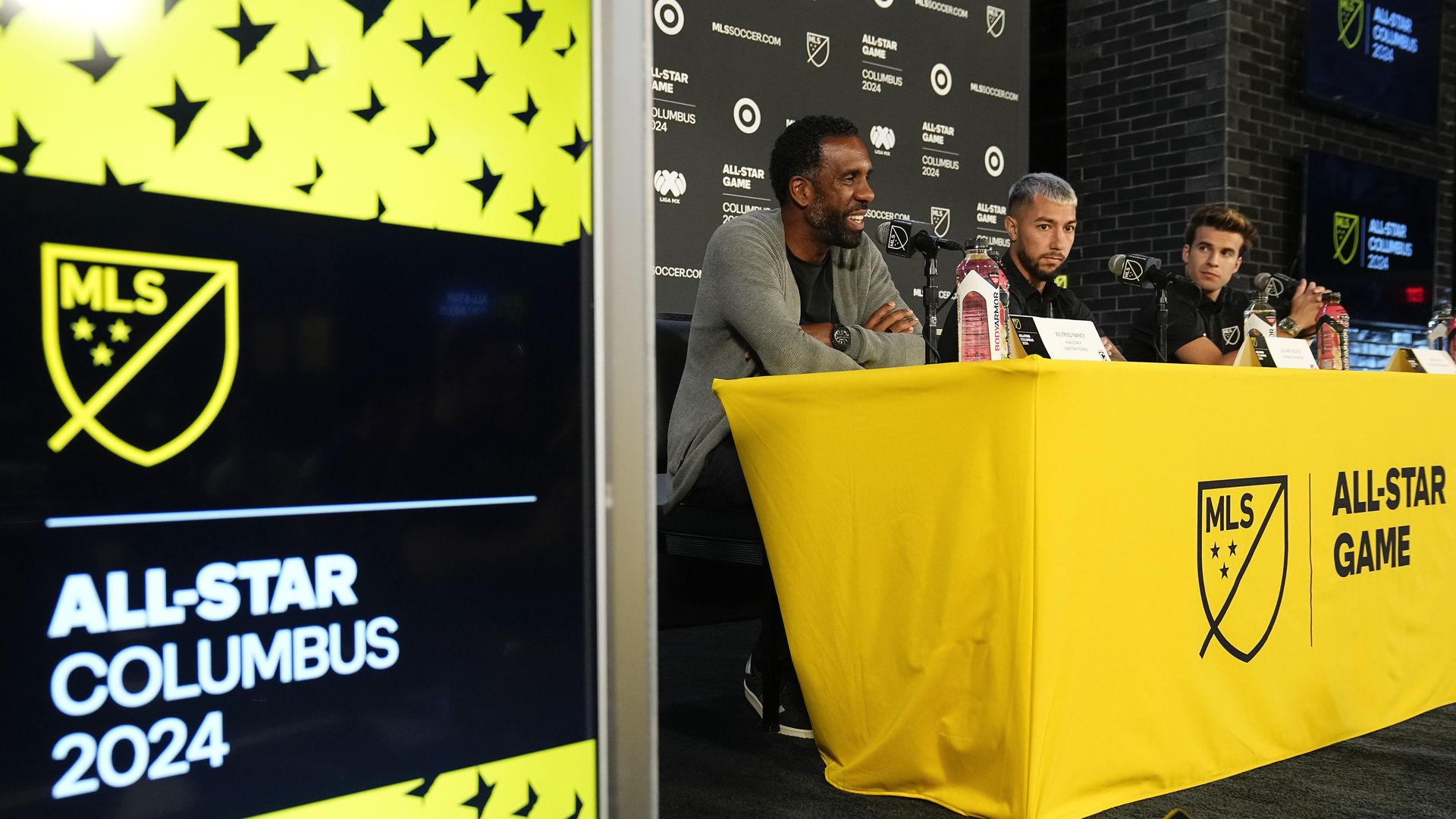 MLS coach and players at a yellow table. 