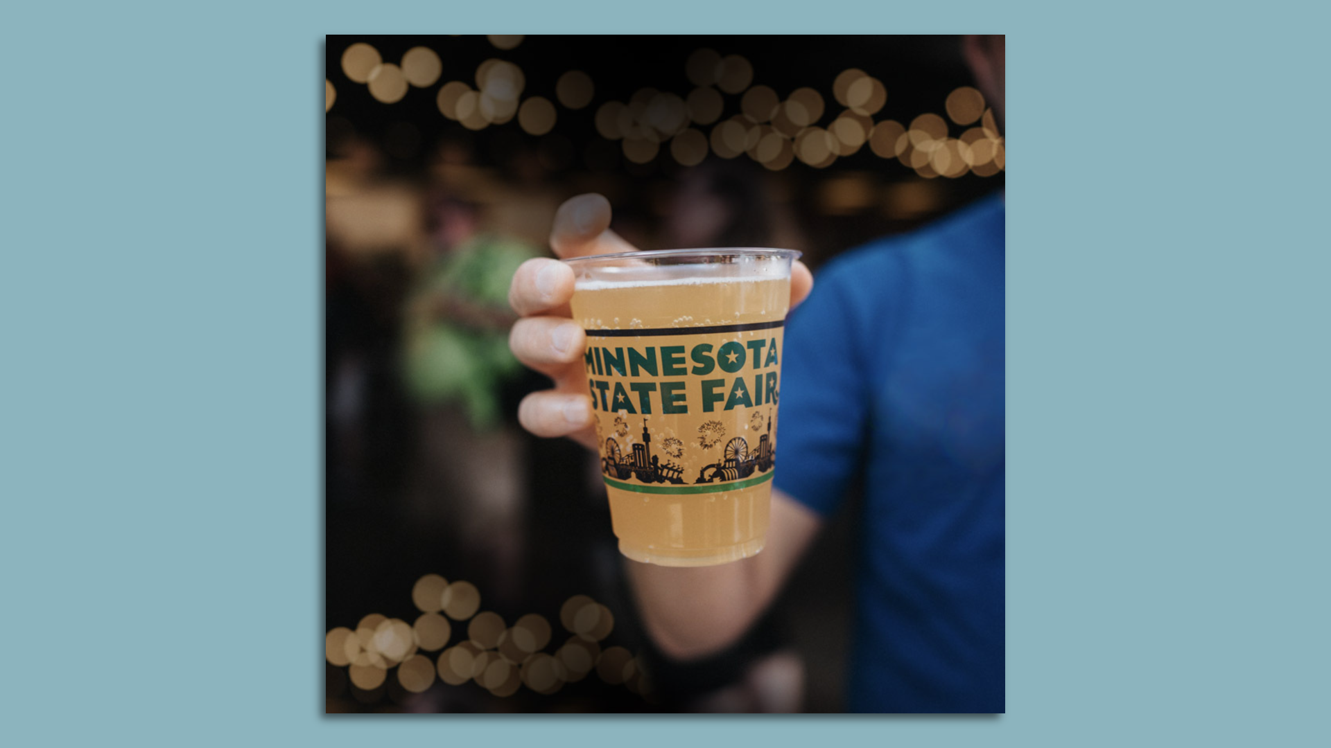 a hand holding a beer in a plastic cup that says minnesota state fair