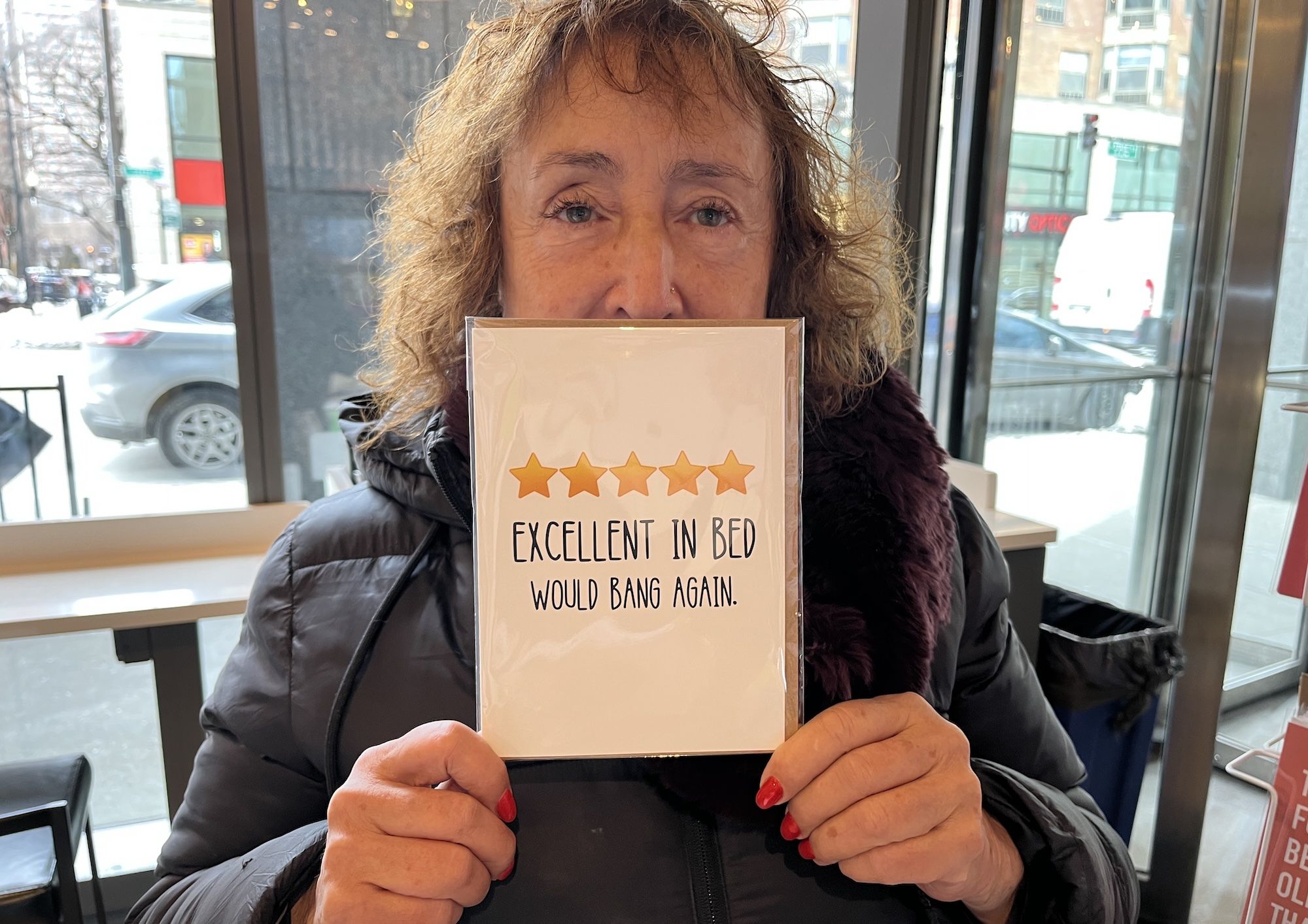 Woman holding a card that reads: "Excellent in Bed, Would Bang Again"