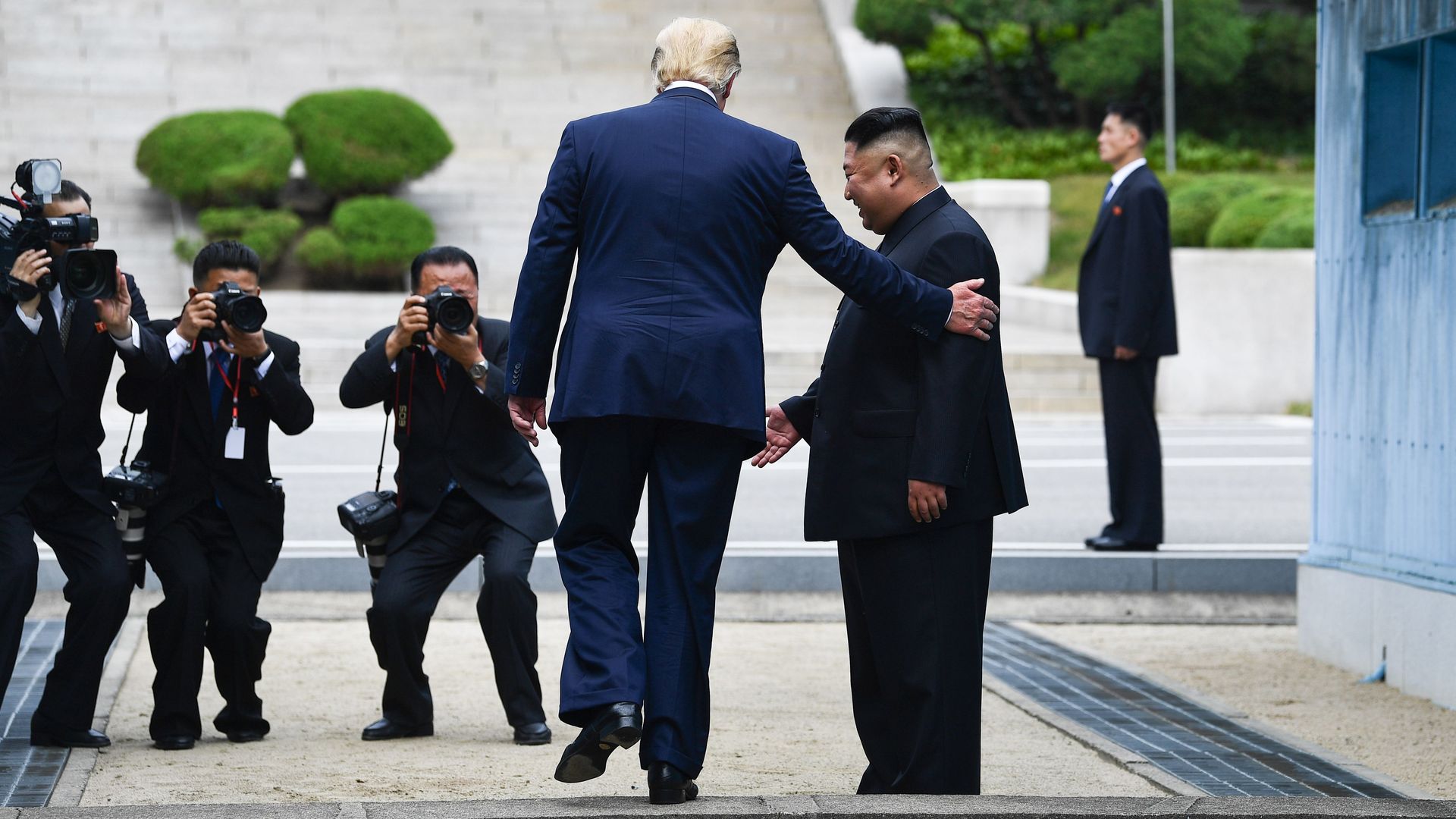 In this image, Trump touches Kim Jong-un's shoulder while walking
