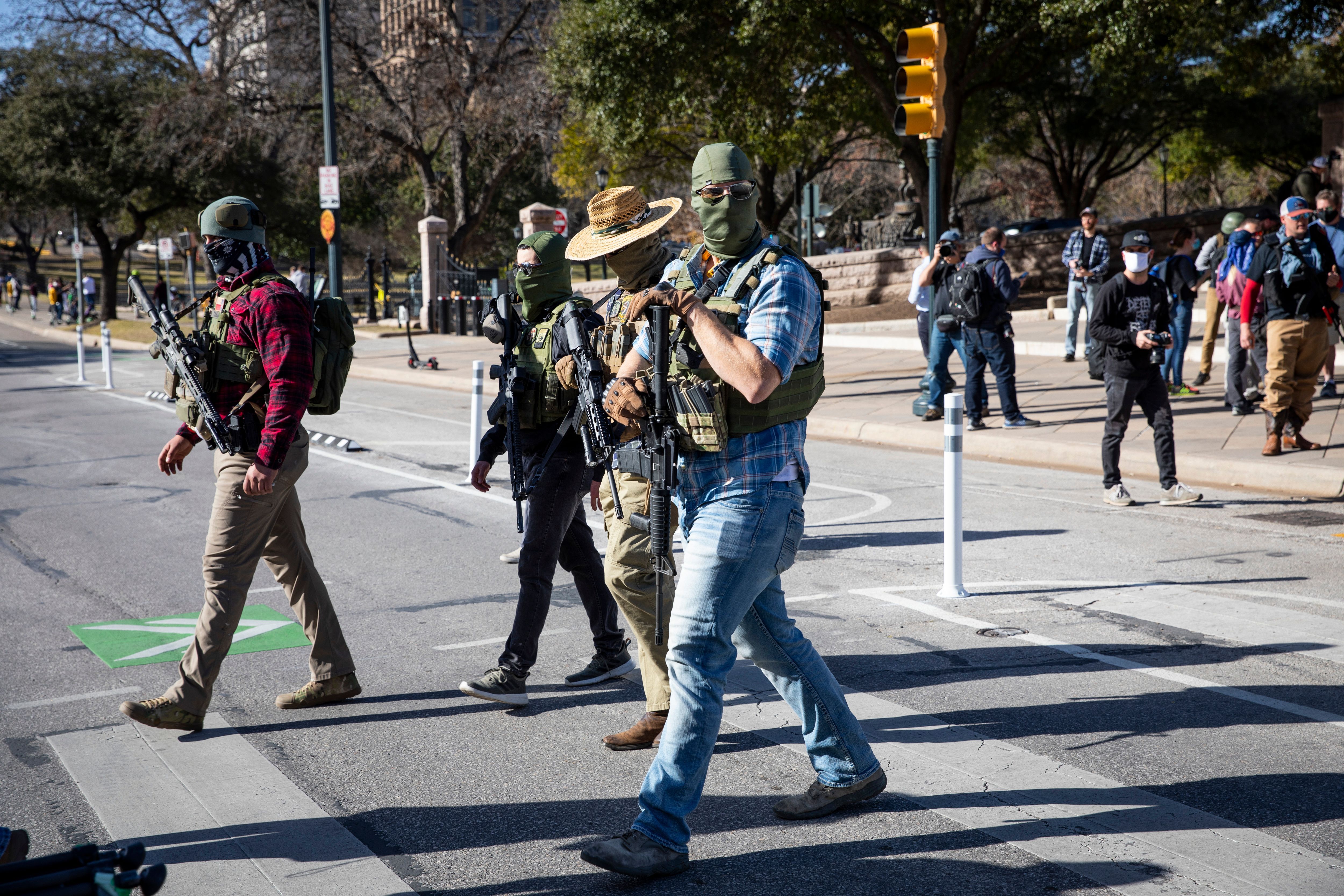 Armed groups cross the street as they hold a rally in front of a closed Texas State Capitol in Austin, Texas,on January 17