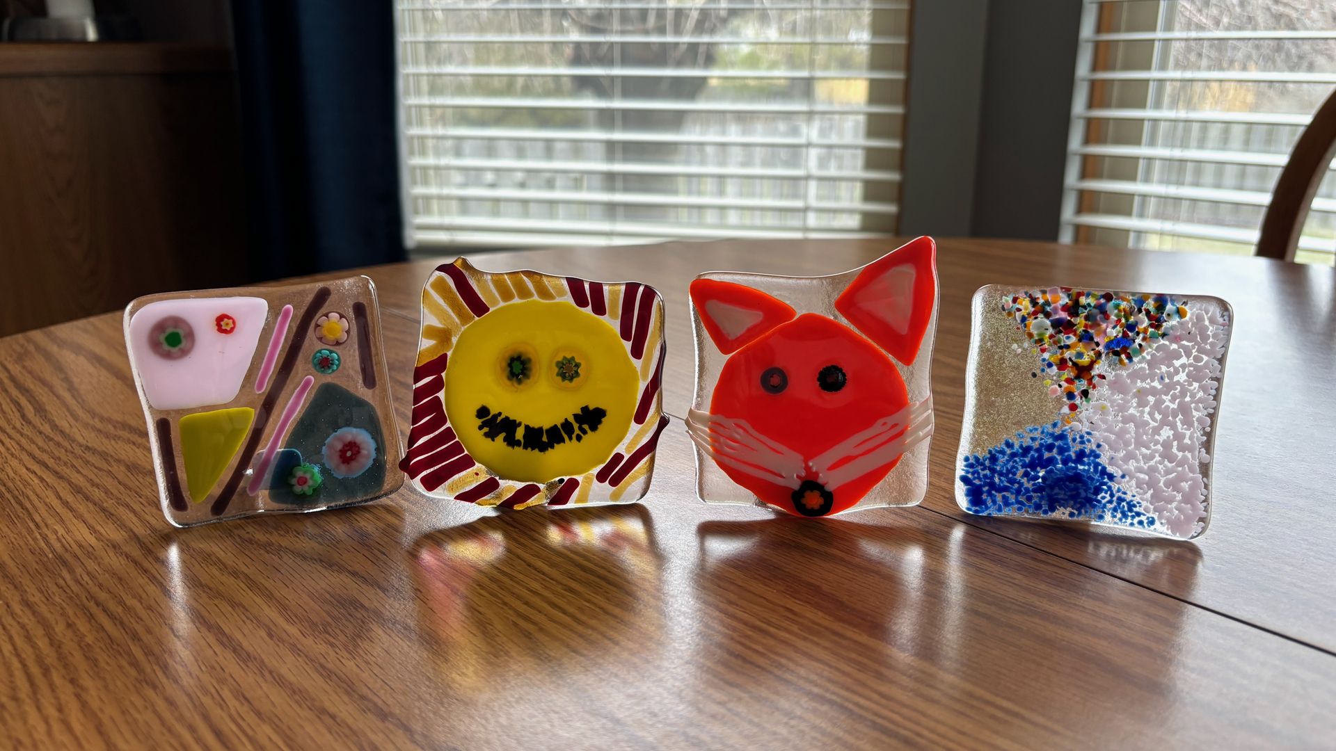 Four glass night light plates — two with abstract designs, one shaped like a fox head and one shaped like a smiling sun