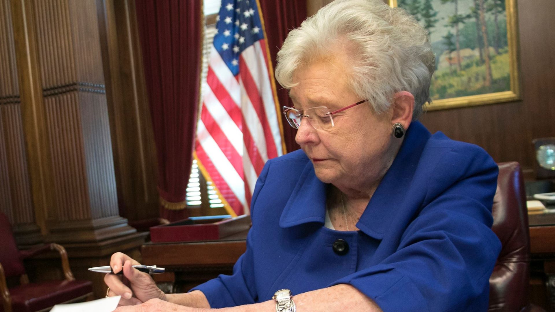 Alabama Gov. Kay Ivey signs a book.