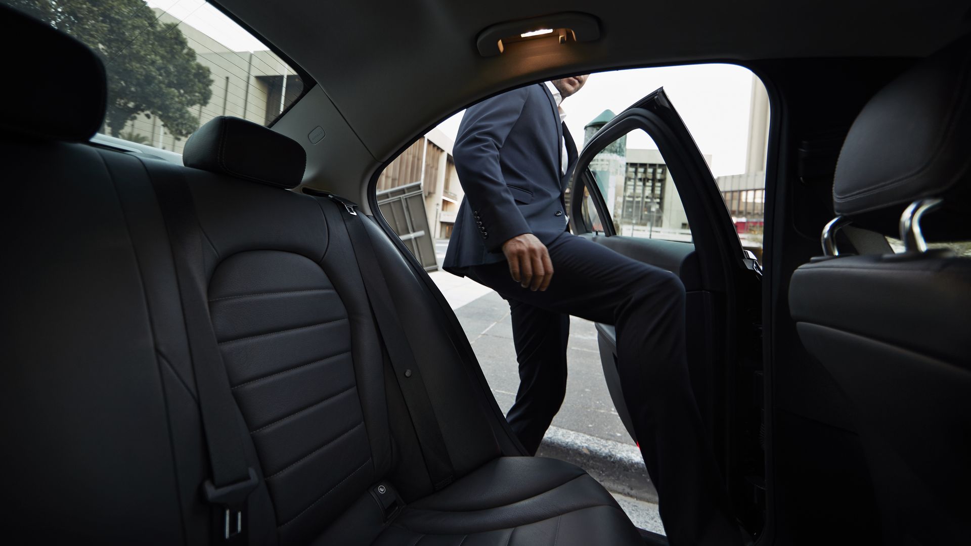 Businessman getting into backseat of a private cab.