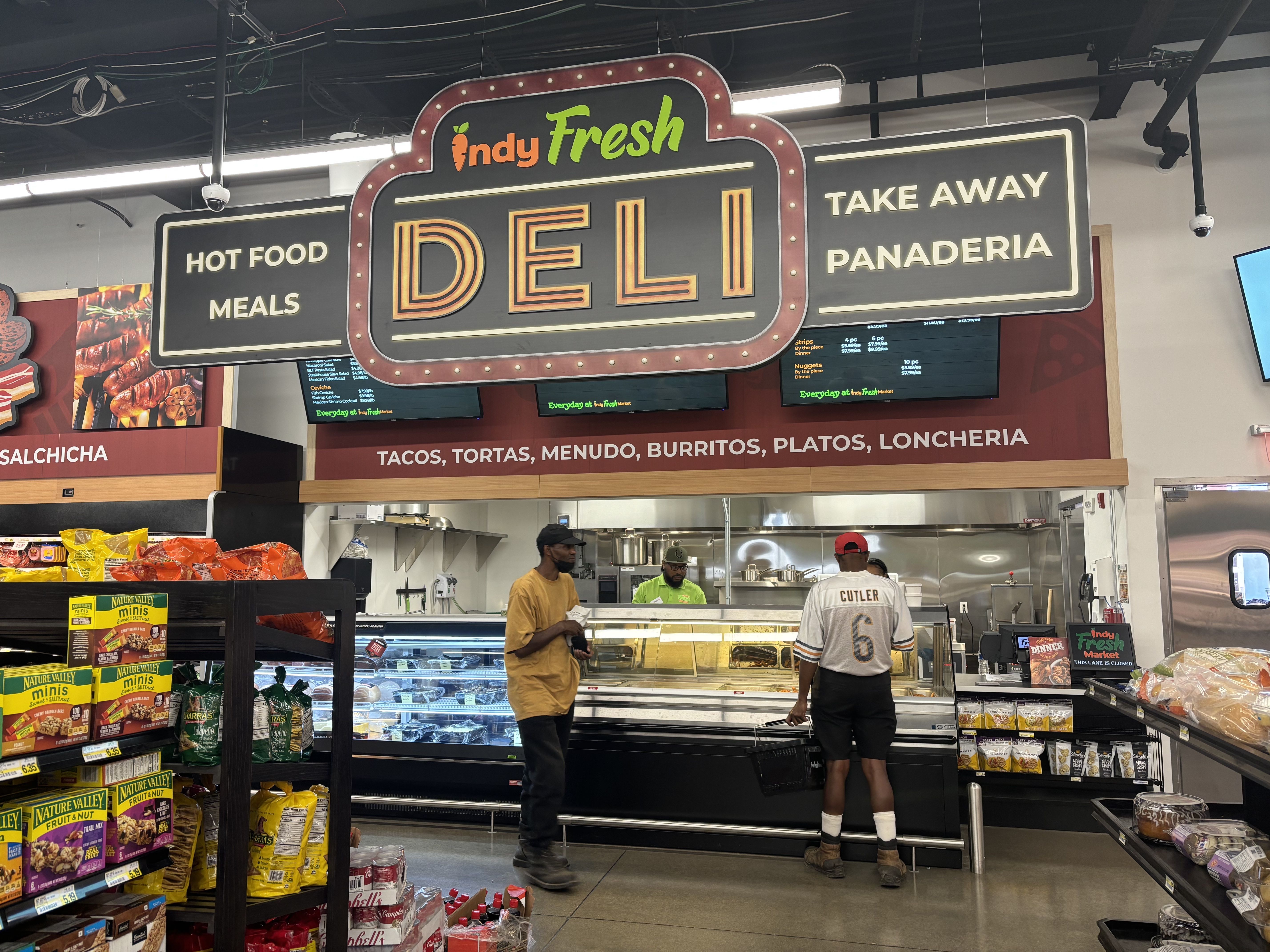 A deli counter with shoppers inside a grocery