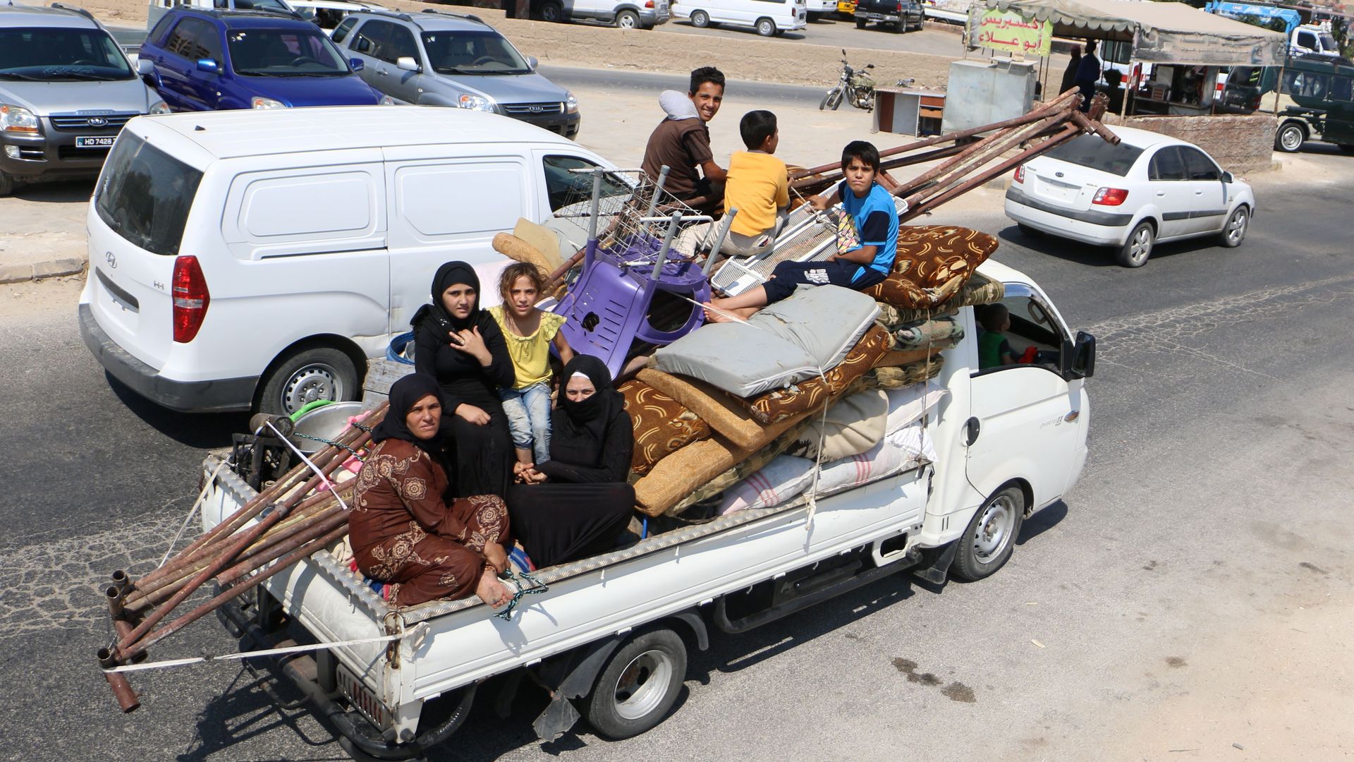 Displaced Syrians who fled from regime raids ride in a truck with their belongings arrive near a camp in Kafr Lusin near the border with Turkey